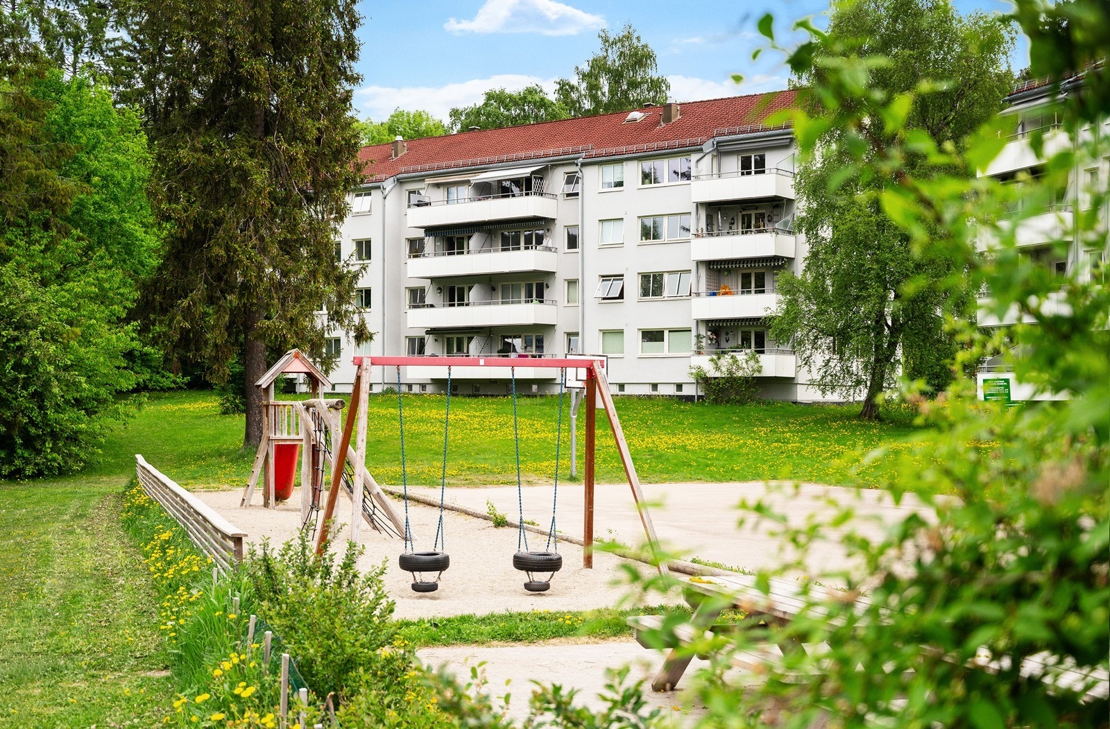 Bak bygget er det gressplen og hyggelige områder med lekeplass og sittegrupper Galleribilde