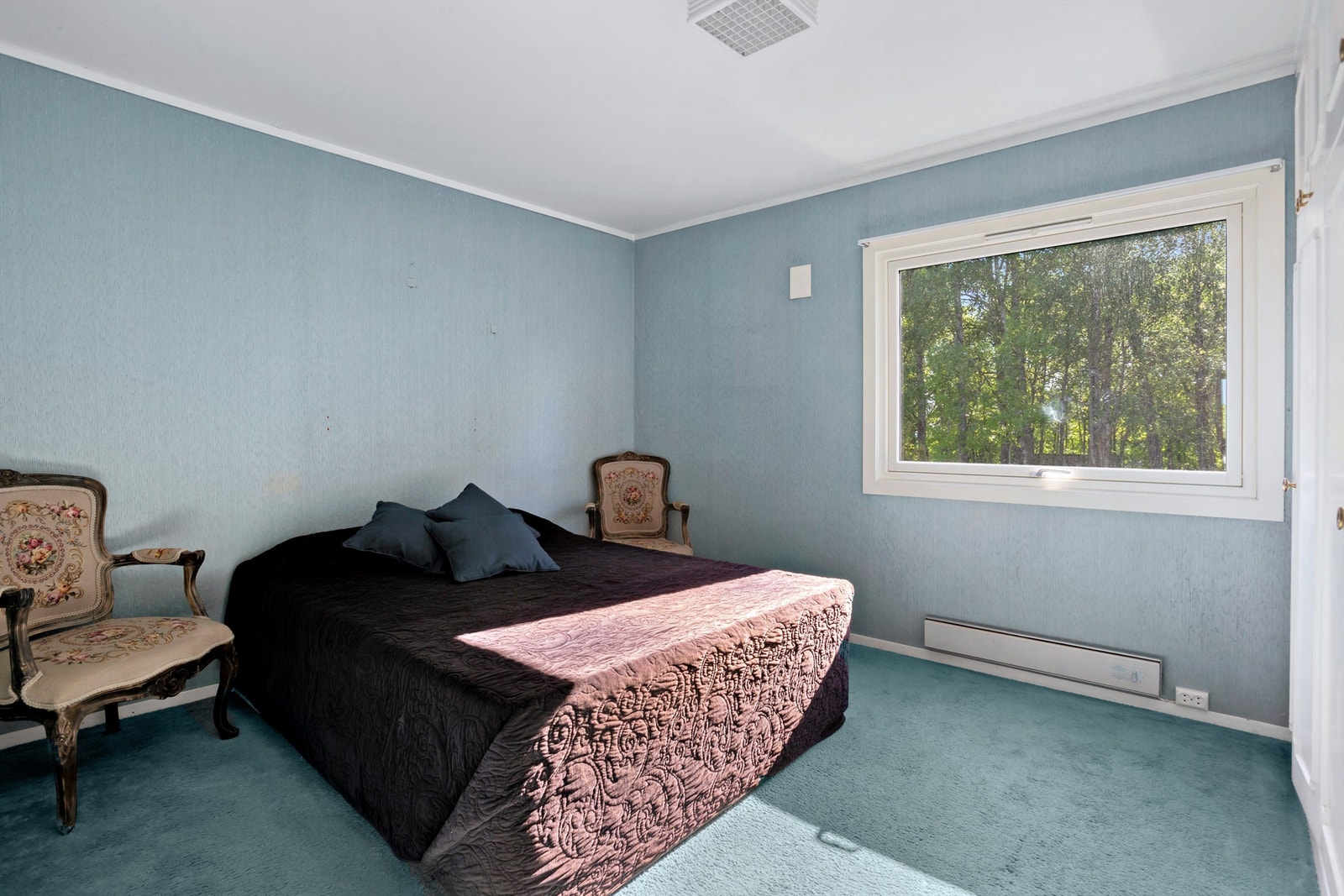 Romslig og tilbaketrukket soverom med plass til stor seng, nattbord og klesskap Galleribilde