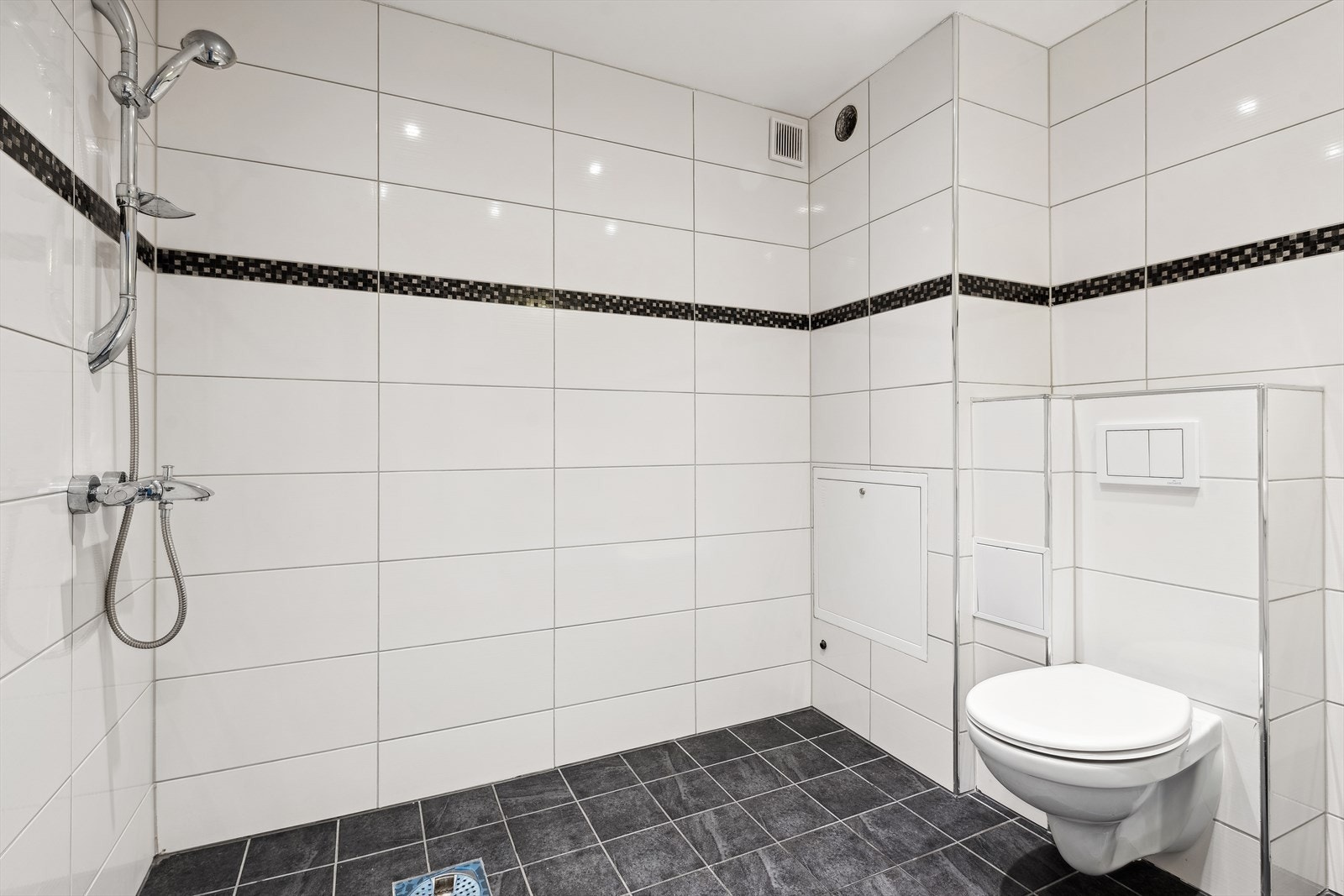 Badet er utstyrt med servant, dusj, toalett, baderomsinnredning med glatte overflater og speil med lys. Galleribilde