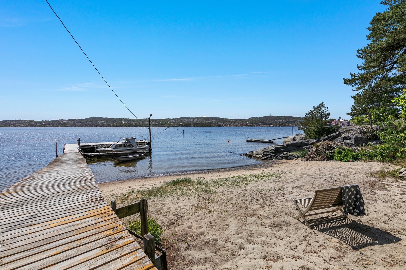 Boligen har tilhørende dyptvannsbrygge og tomten grenser til en fin badestrand Galleribilde