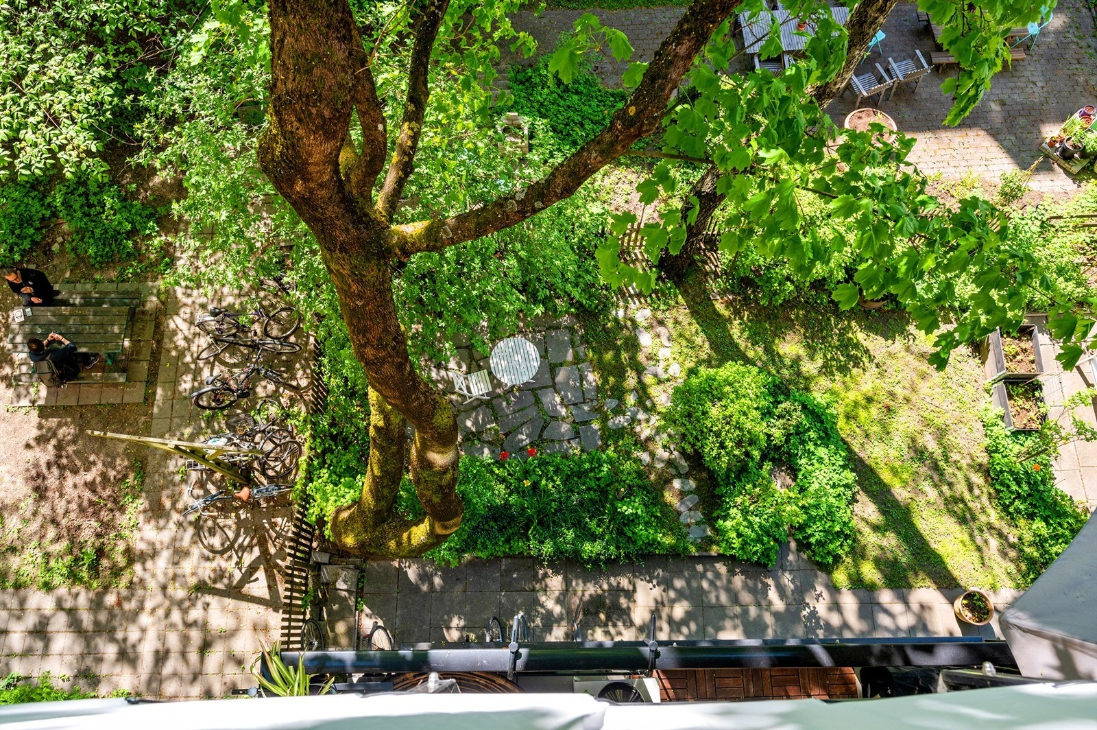 Flott utsyn til sameiets hyggelige bakgård fra balkongen. Her er det sittegruppe, sykkelparkering og hyggelig beplantning. Galleribilde