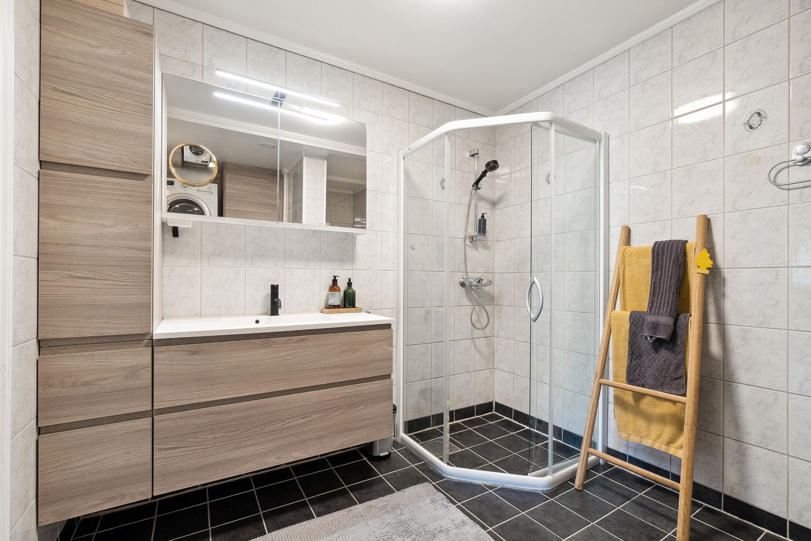 Stort bad/vaskerom med flislagt gulv og vegger. Galleribilde