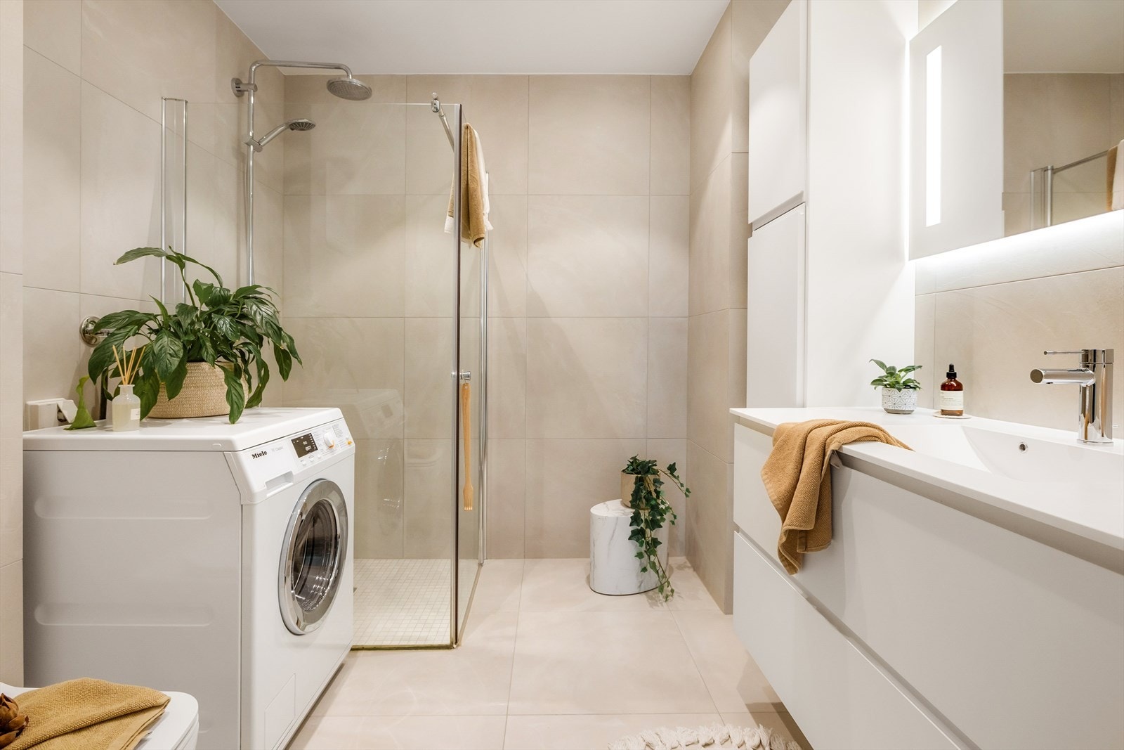 Et elegant baderom utført med lekre fliser på gulv - og veggflater som harmonerer pent med den hvite innredningen. Galleribilde