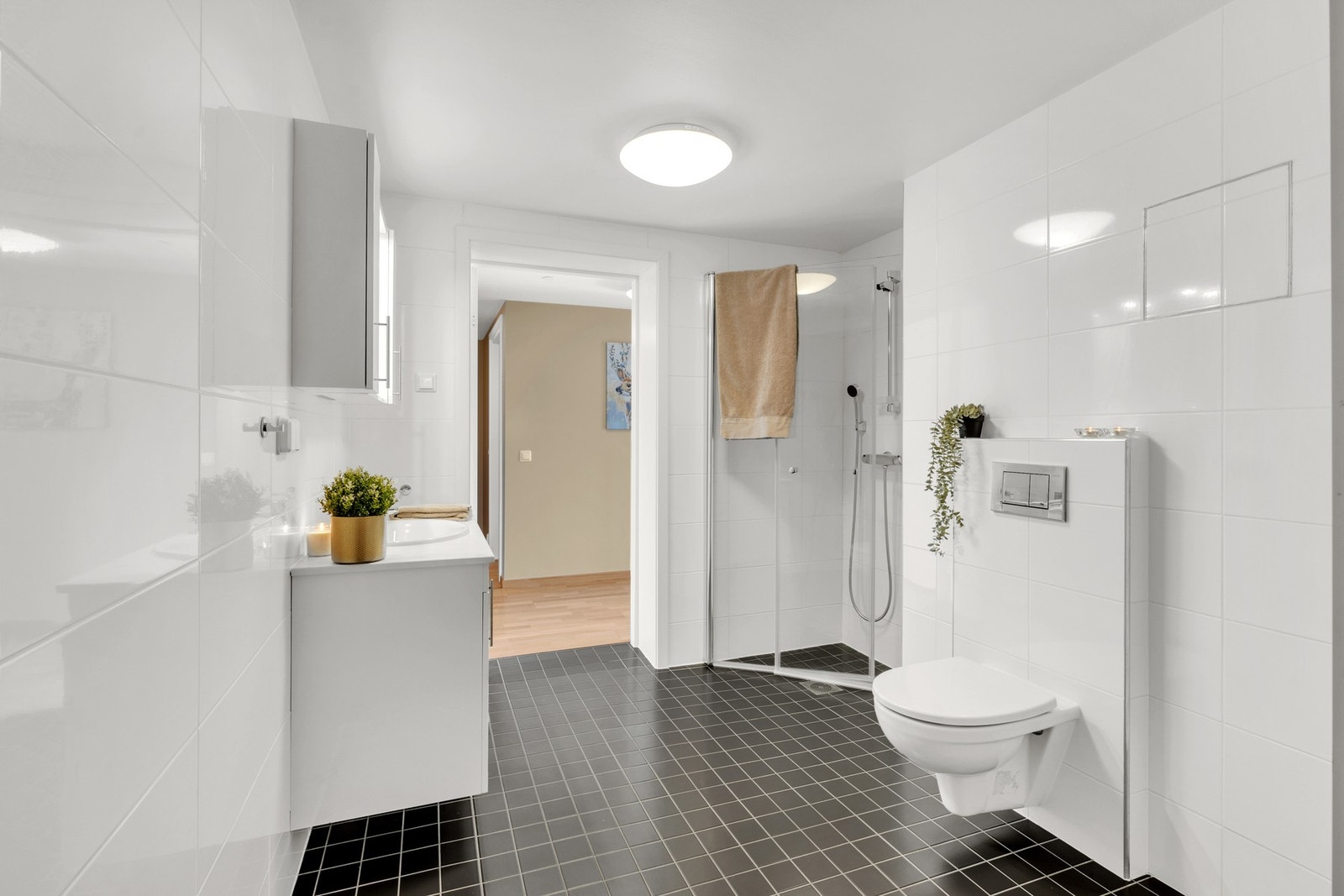 Her får du veggmontert WC, dusjhjørne og lys baderomsinnredning med mye lagringsplass. Galleribilde