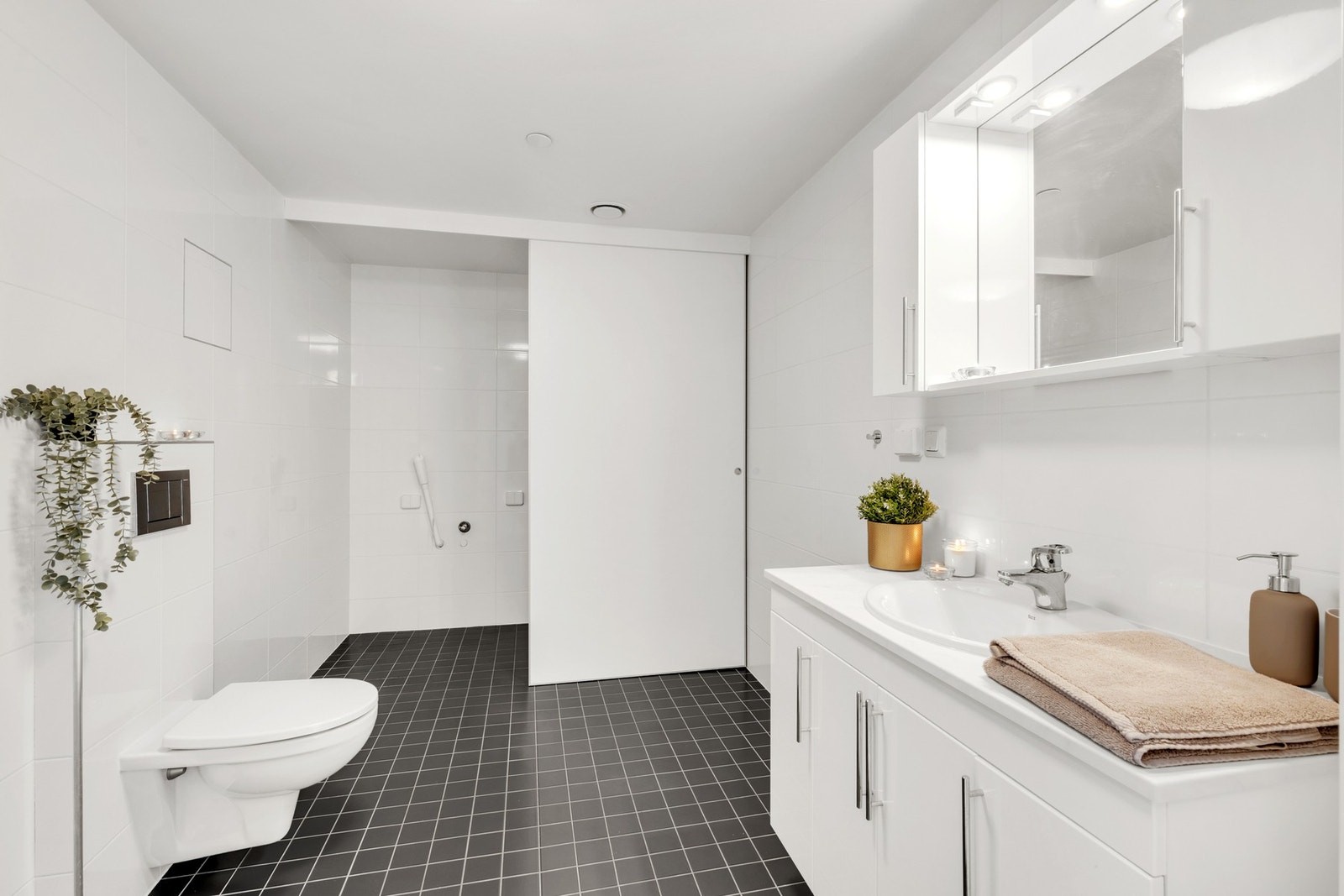 Svært flott bad med flislagte flater og varmekabler i gulv. Med hele 8 kvm har det blitt ordnet en praktisk "vaskeavdeling" bak skyvedører. Galleribilde