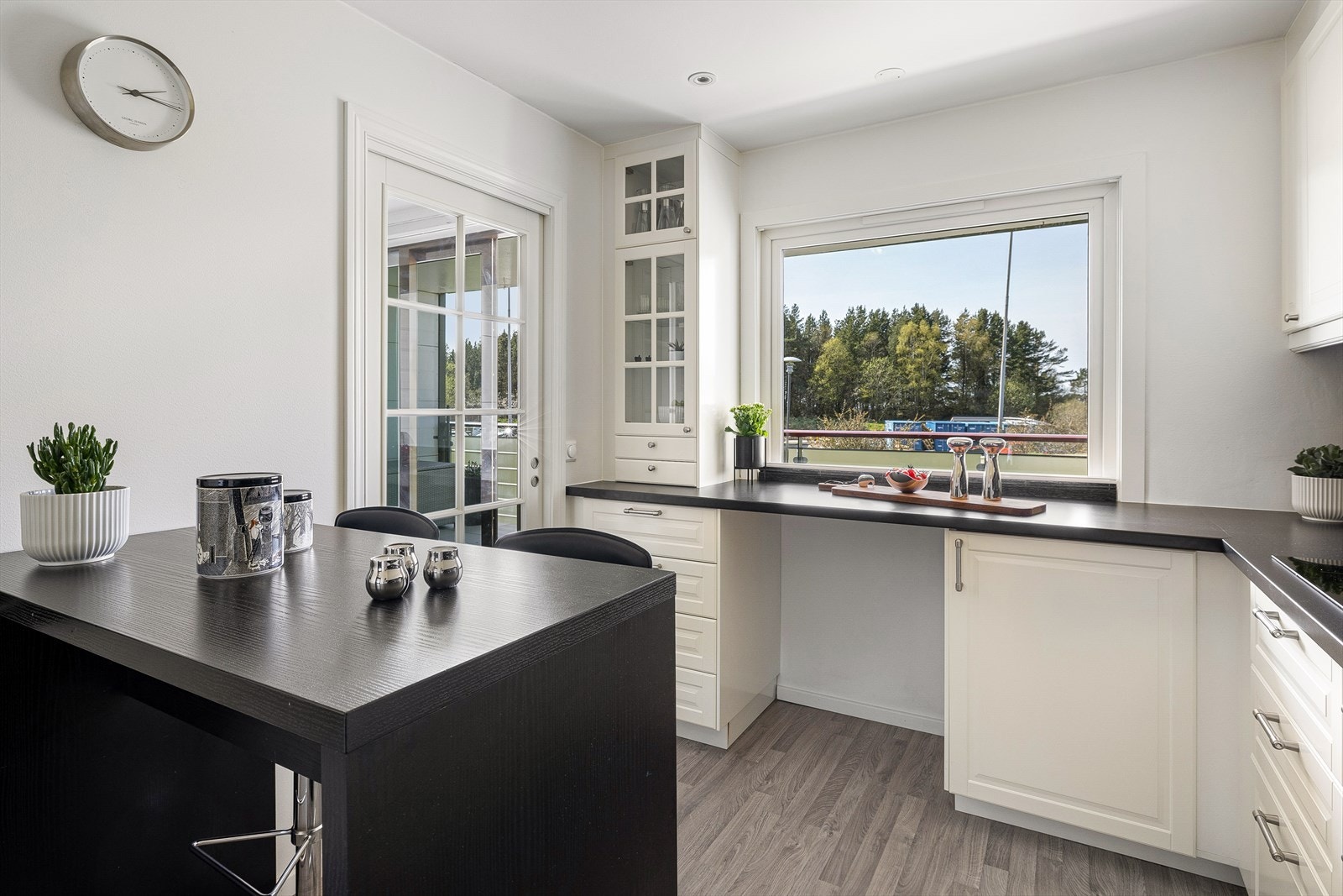 Kjøkkenet består av en klassisk innredning utført med hvite profilerte fronter og benkeplate av laminat med nedfelt vask. Galleribilde