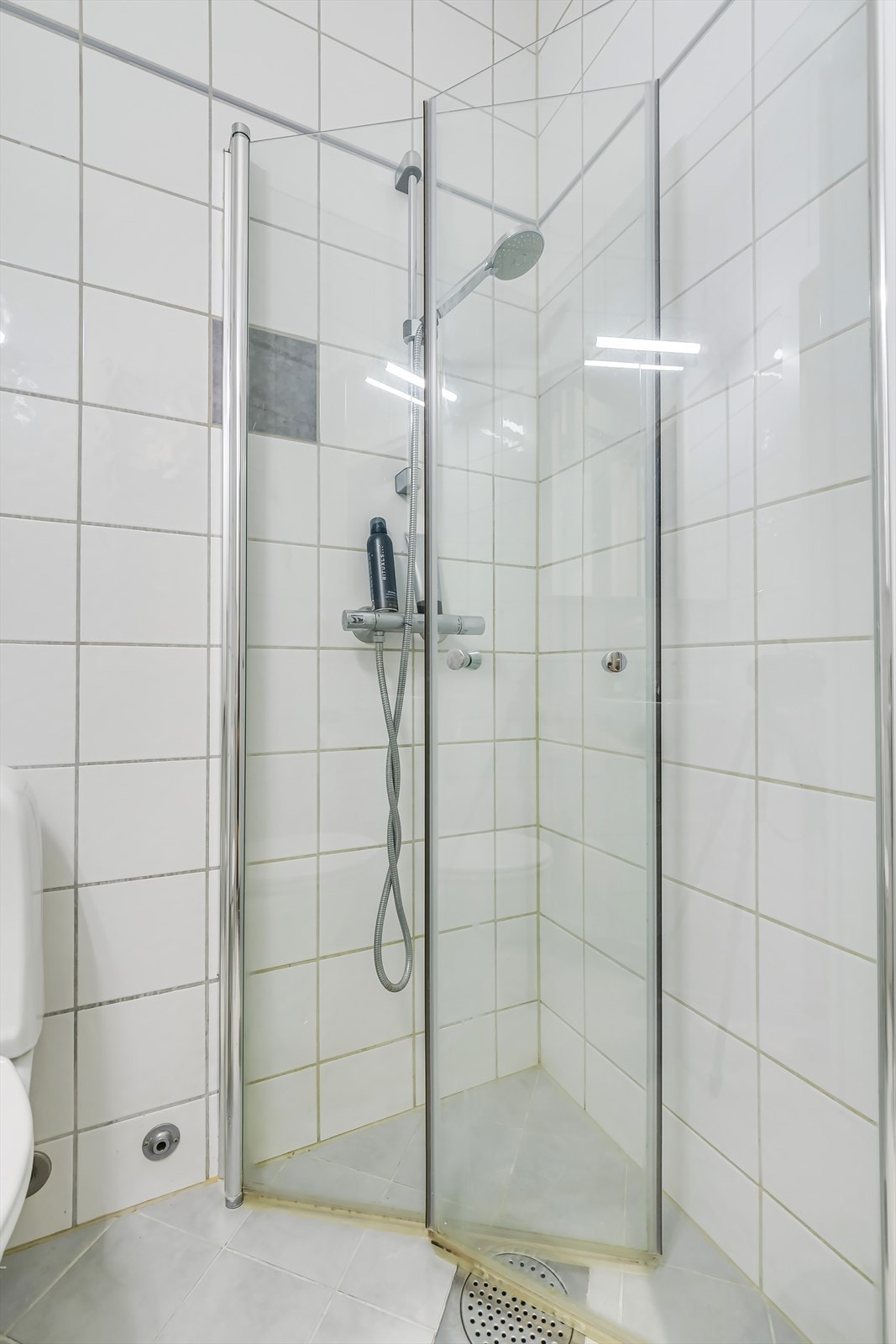 Badet er innredet med servant på underliggende skap, speilskap, dusjhjørne og toalett. Galleribilde