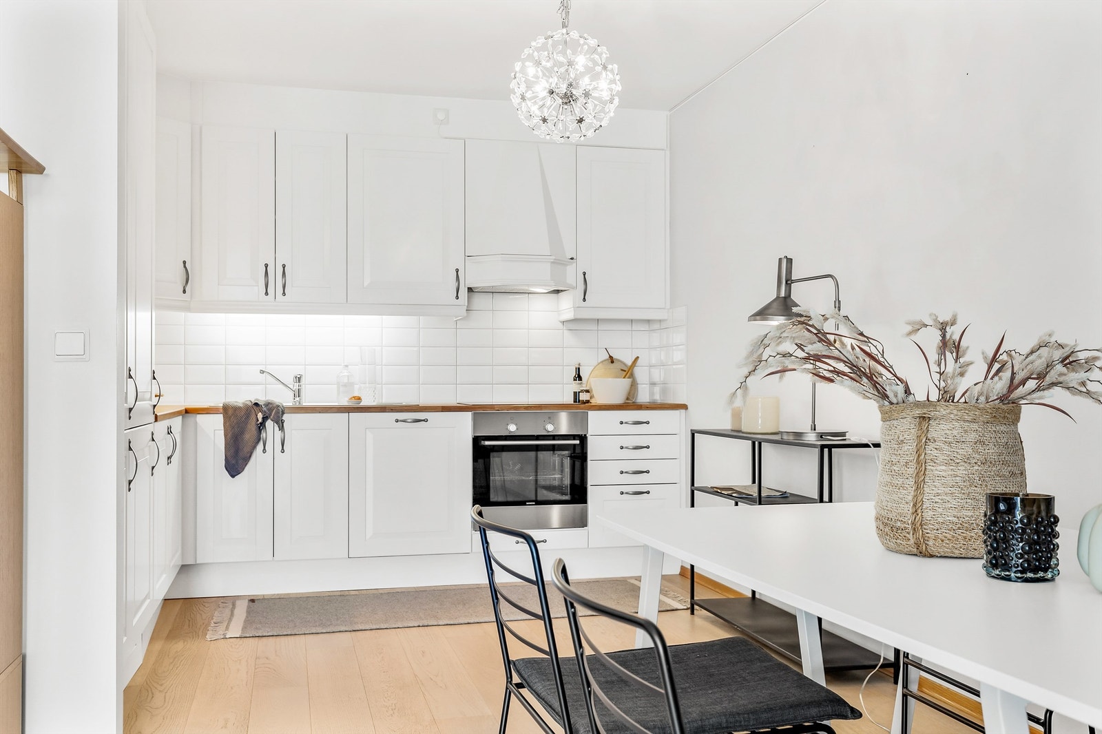 Kjøkkeninnredningen med profilerte hvite fronter fra byggeår i 2012. Benkeplate av tre med nedfelt oppvaskkum i rustfritt stål med ett-greps armatur. Galleribilde