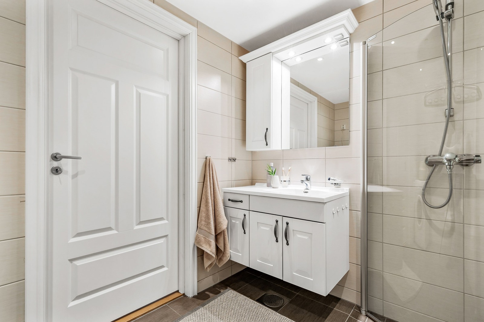 Vegghengt servantskap med ovenpåliggende servant med ett-greps armatur. Dusjsone med innfellbare dører av glass. Galleribilde