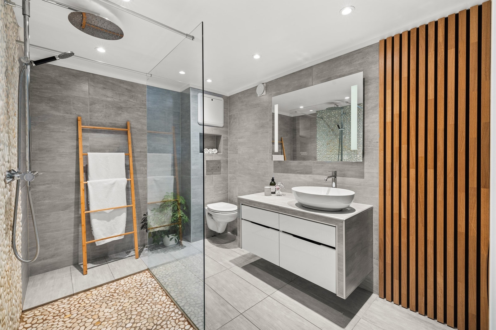 Lekkert baderom med fliser på gulv med gulvvarme, fliser på vegger og nedsenket himling med downlights Galleribilde