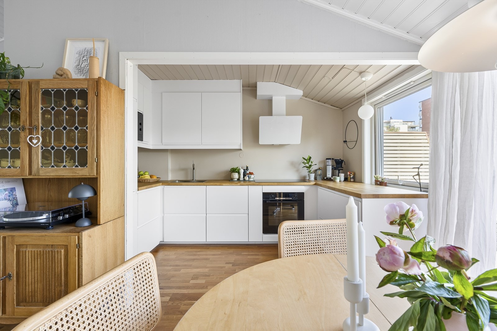 Moderne kjøkken med hvite skap og innebygde hvitevarer, åpen løsning mot lys stue. Galleribilde