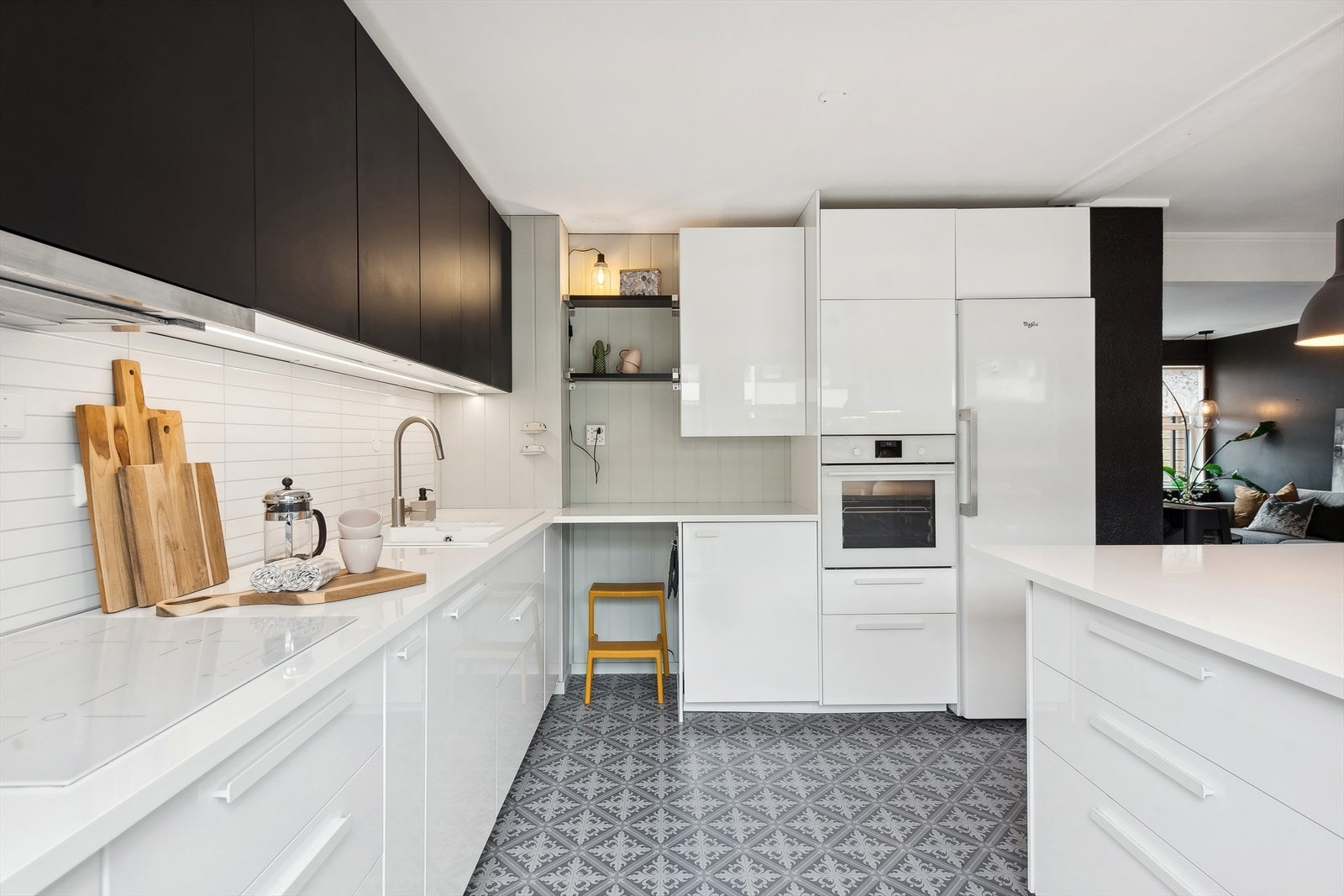 Integrerte hvitevarer i form av stekeovn, platetopp, fryseskap og oppvaskmaskin. Frittstående hvitevarer i form av kjøleskap. Plater av høytrykkslaminat med flismønster i benkerygg. Kjøkkenventilator over platetopp. Avtrekk ut gjennom yttervegg. Galleribilde