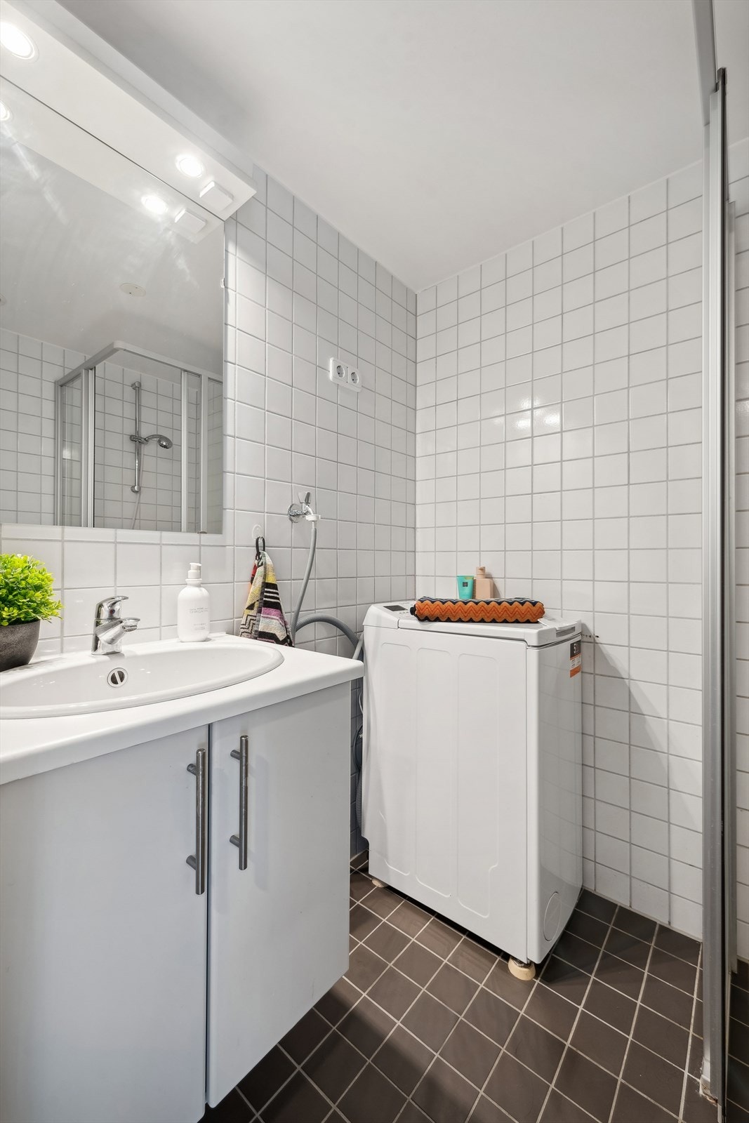 Baderomsinnredningen har slette fronter og nedsenket servant med ett-greps blandebatteri. Det er opplegg for vaskemaskin. Galleribilde