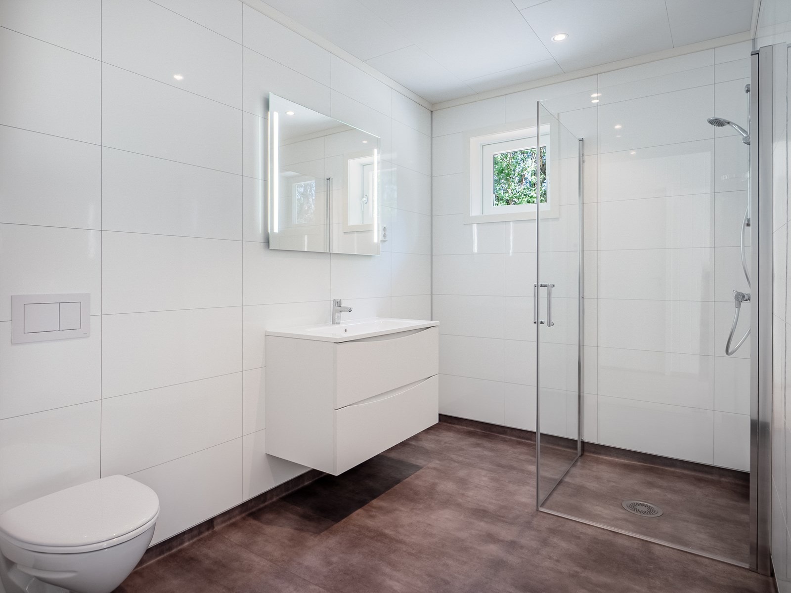 Lekkert bad innredet med servant på innredning, vegghengt toalett og dusjhjørne. Galleribilde