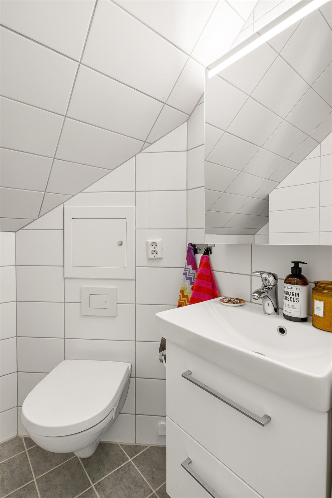 Badet er innredet med dusj, servant i møbel, servantskap med lys og veggmontert toalett. Galleribilde