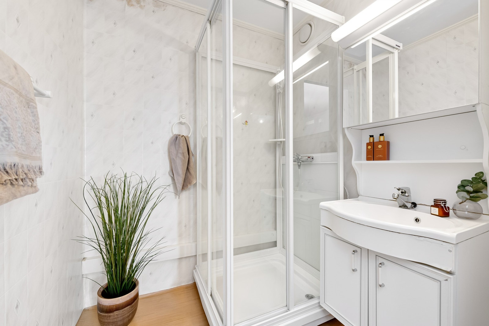 Badet har gulvbelegg med varmekabler, tapetserte vegger og malt himling. Baderomsinnredning og dusjkabinett Galleribilde