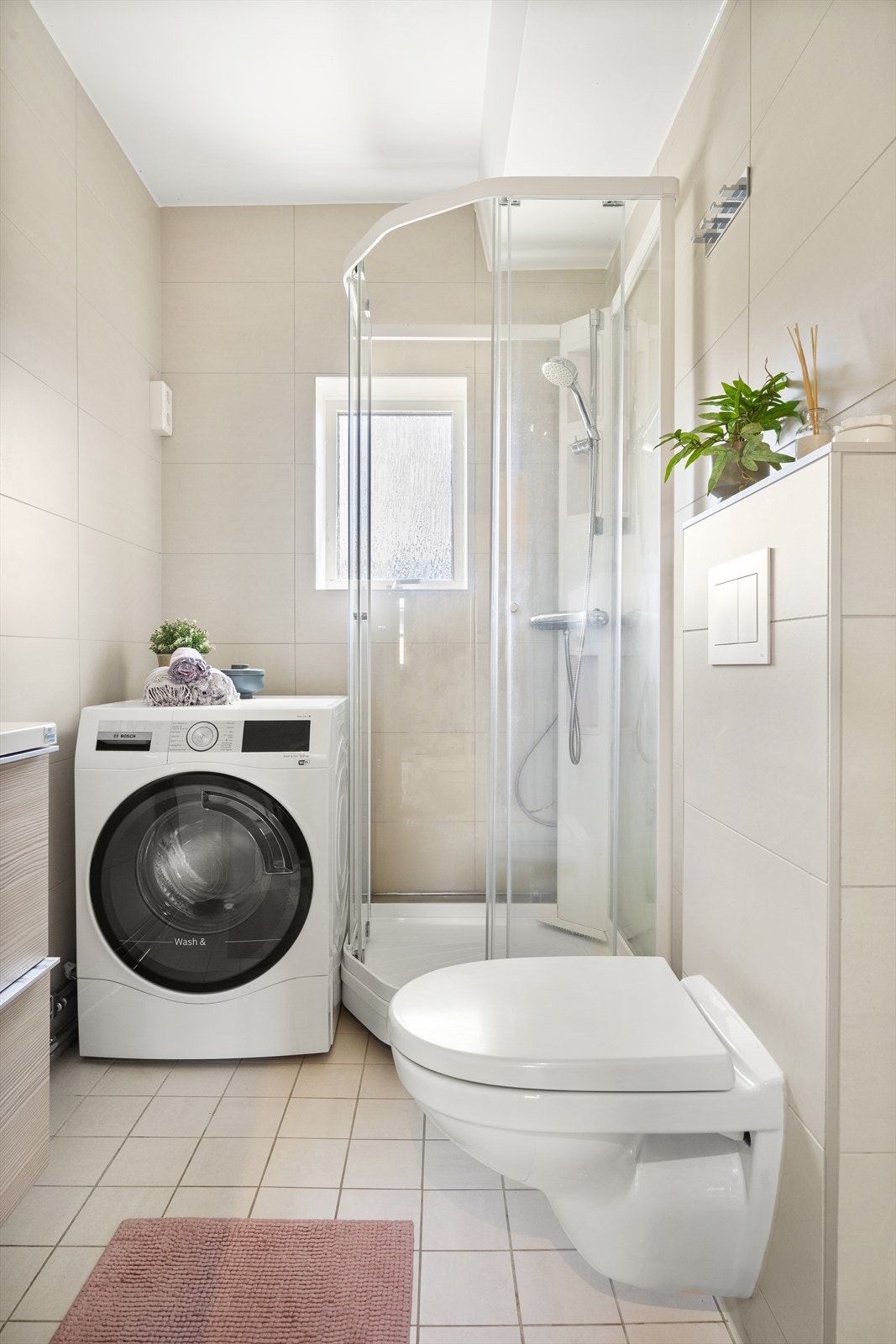 Stilig bad med gulvvarme, veggehengt WC, opplegg vaskemaskin og smart dusjkabinett som beskytter vindu, vegger og gulv for vannsøl/-sprøyt. Galleribilde