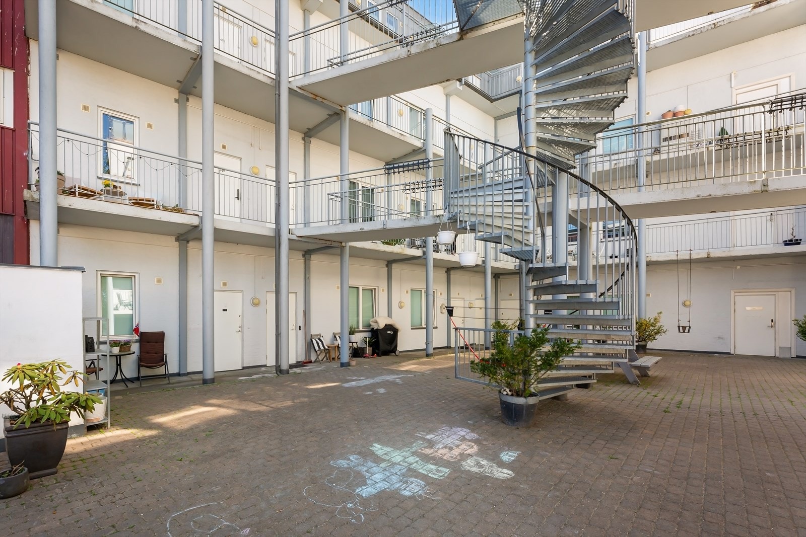 Pent opparbeidet bakgård med sittegrupper, beplantning og sykkelparkering. Galleribilde