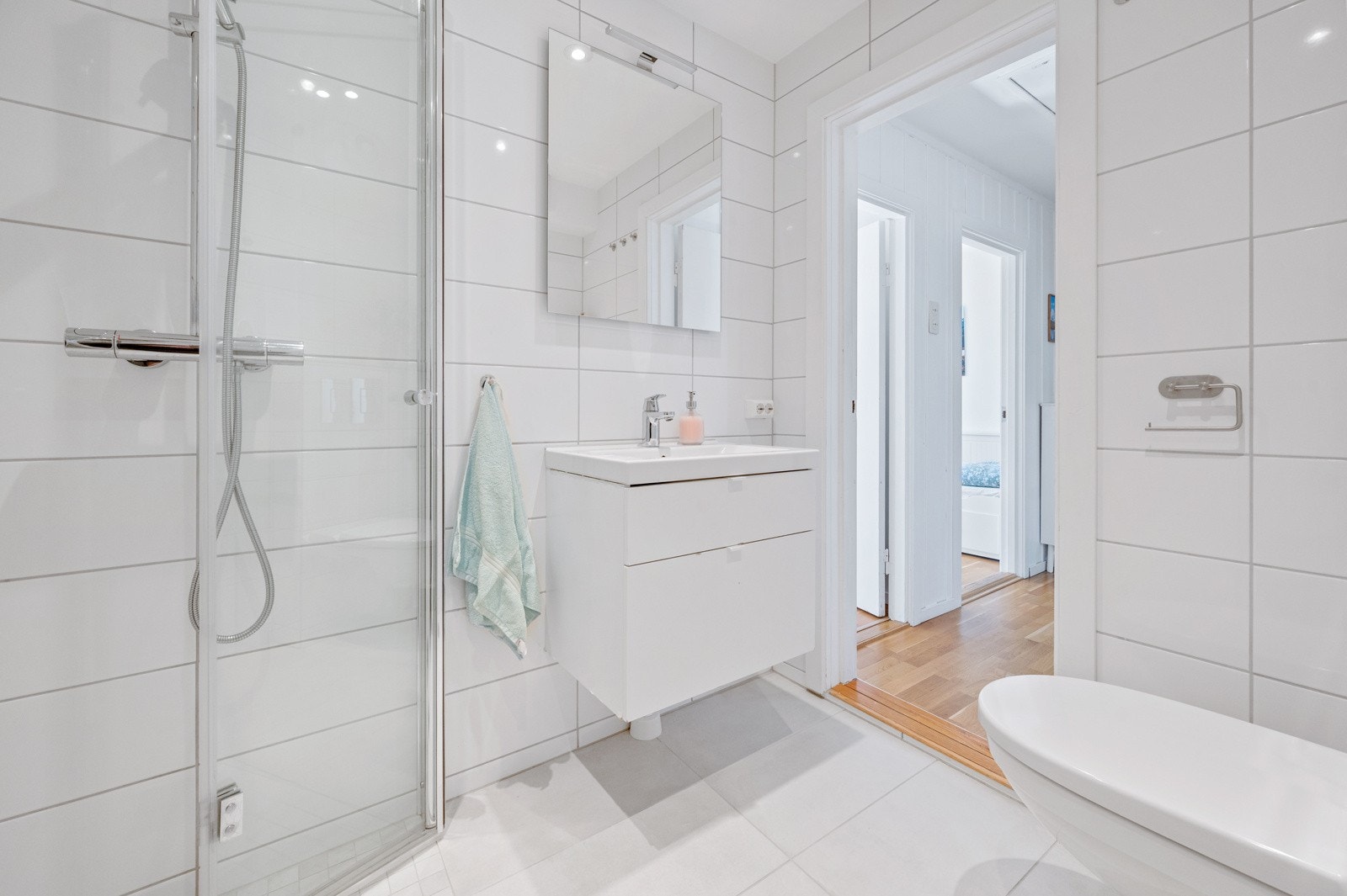 Innredning med slette fronter og heldekkende servant. Skapplass og speil med belysning på vegg. Avtrekksvifte. Galleribilde