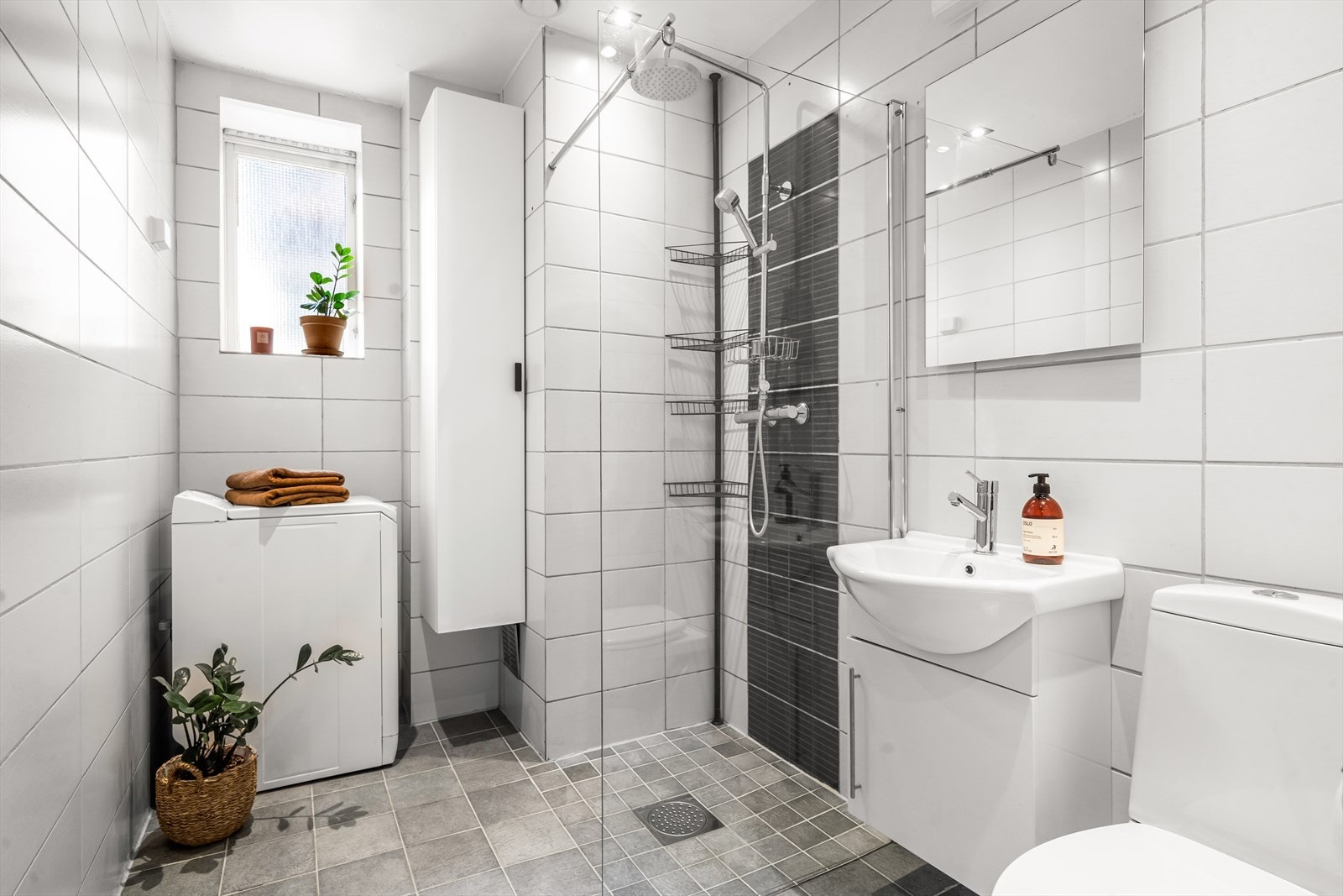 Baderommet er tidløst og pent flislagt med varme i gulv. Innredning med frittstående klosett, servantinnredning, servant med ettgreps blandebatteri, dusjdører, dusjarmatur, opplegg og plass til vaskemaskin. Galleribilde