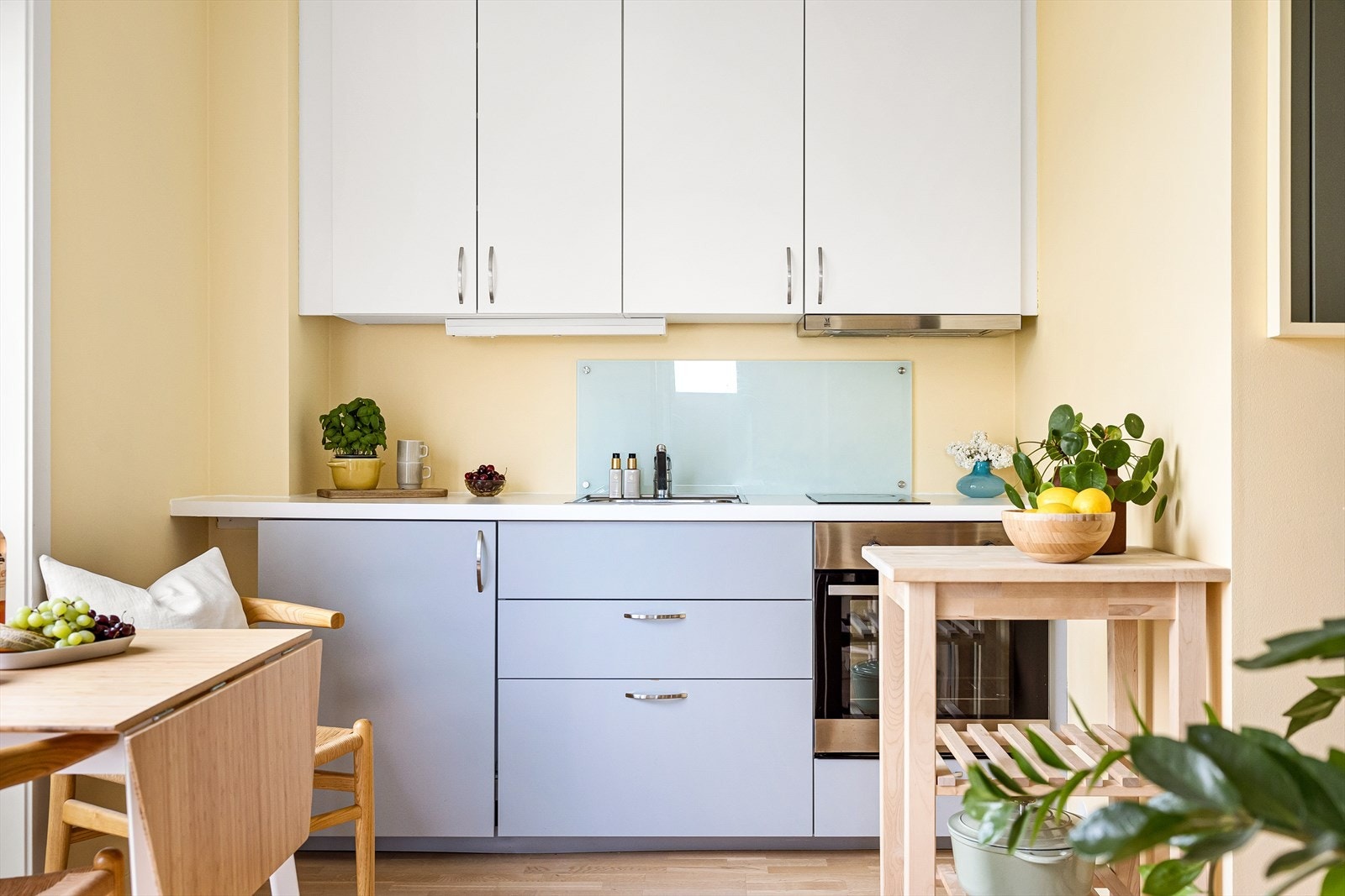 Moderne og stilren kjøkkeninnredning bestående av glatt laminert kjøkkeninnredning, lys under overskap, kullfiltervifte over integrert koketopp, to plater/integrert ovn, laminert benkeplate, kum med ettgreps blandebatteri og integrert kjøleskap. Galleribilde