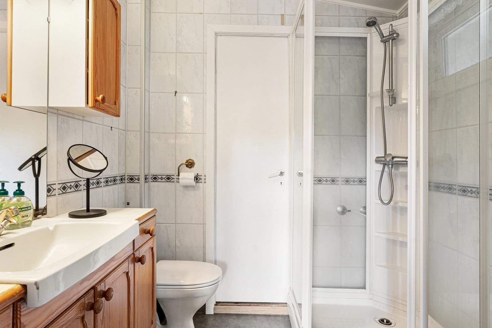 Baderom som inneholder toalett, dusjkabinett og baderomsinnredning med vask og speil. Galleribilde