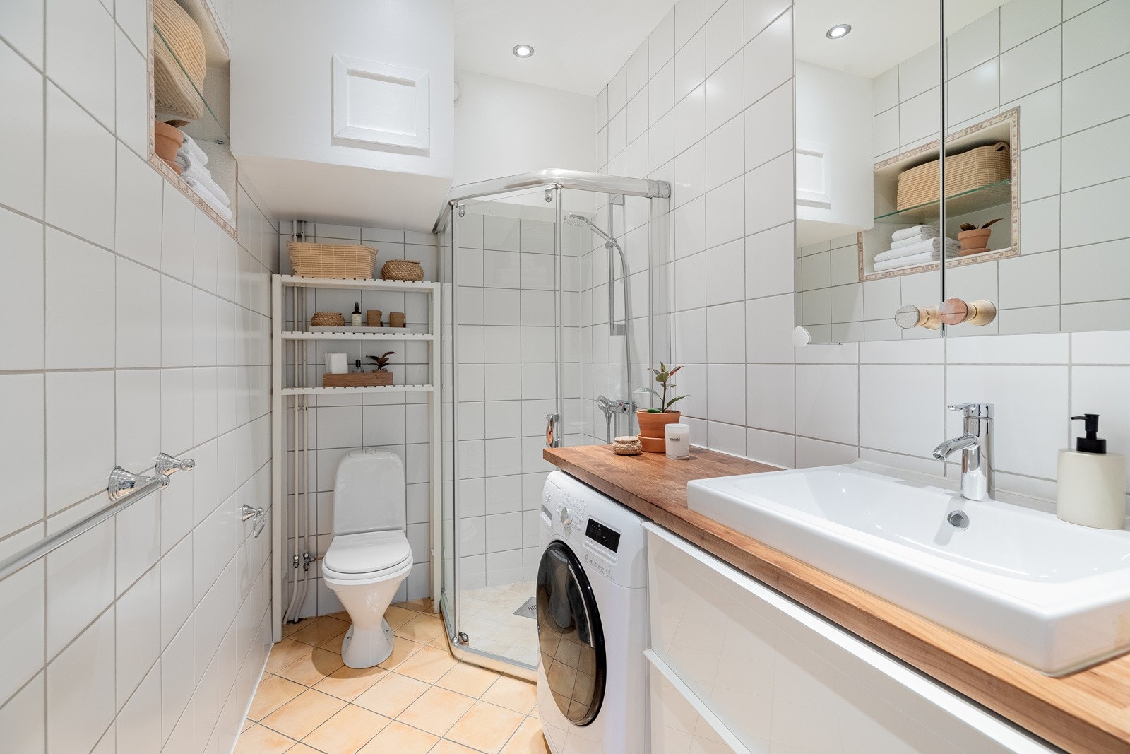 Lyst flislagt bad med vegghengt servantskap i høyglans, speilskap og downlights Galleribilde