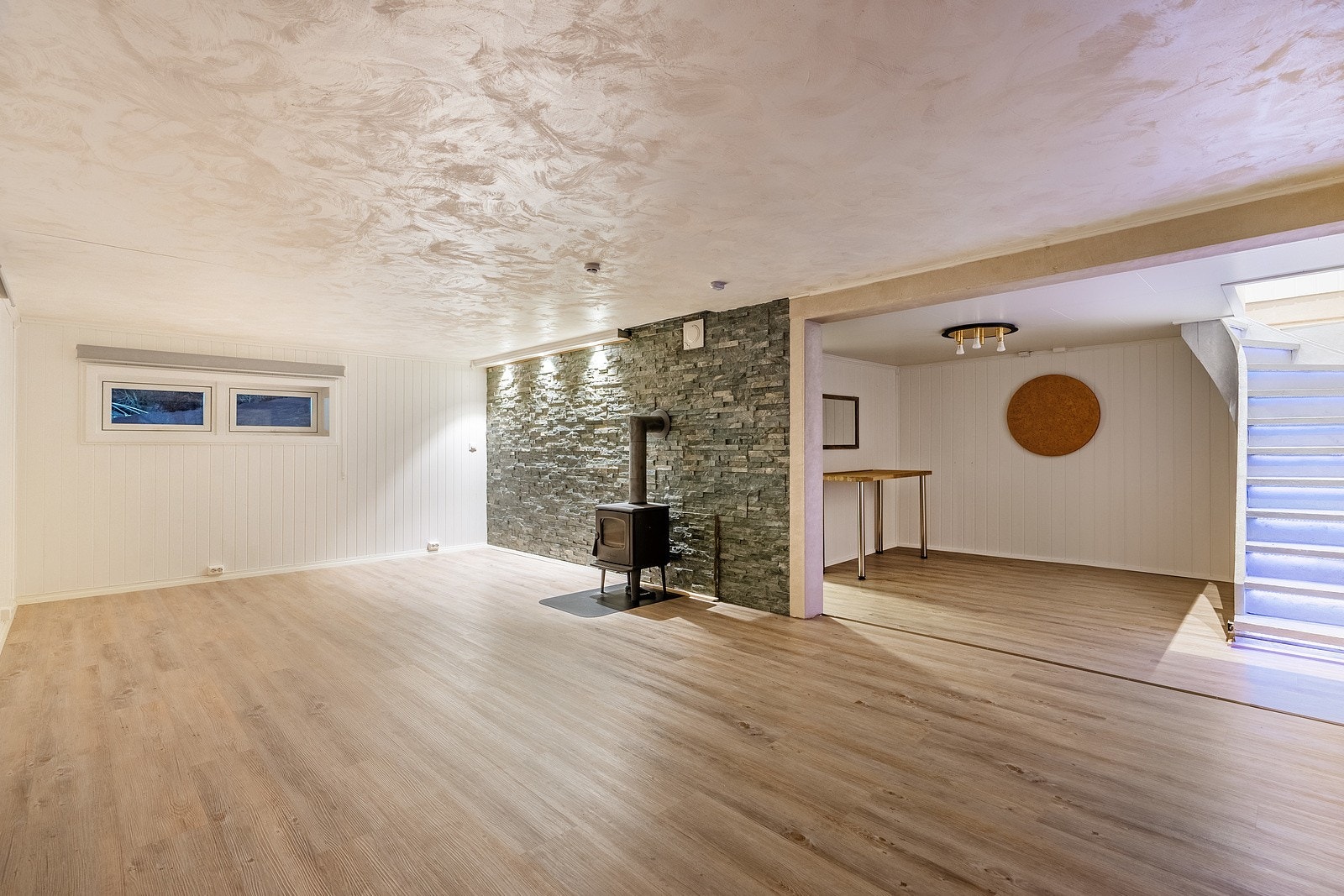 Rommet har god plass til å etablere flere sosiale soner. Det finnes også en flott peisovn som varmer godt og lenge. Galleribilde