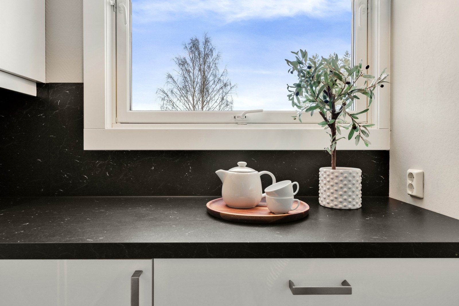 Innredningen har glatte fronter og sort benkeplate av laminat med matchende kitchen boards over benken Galleribilde