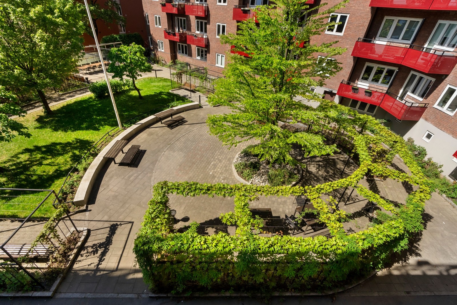 Meget pent opparbeidet bakgård med sittegrupper, gressplen, prydbusker og stenlagte gangveier. Galleribilde