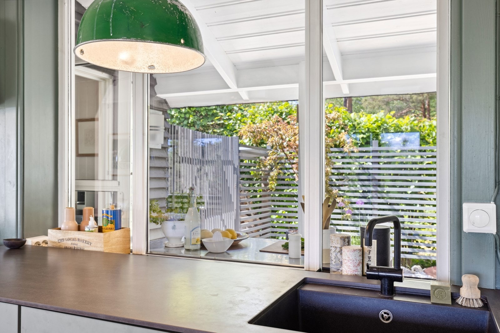 Utsikt fra kjøkkenet ut mot det koselige utekjøkkenet og terrassen Galleribilde