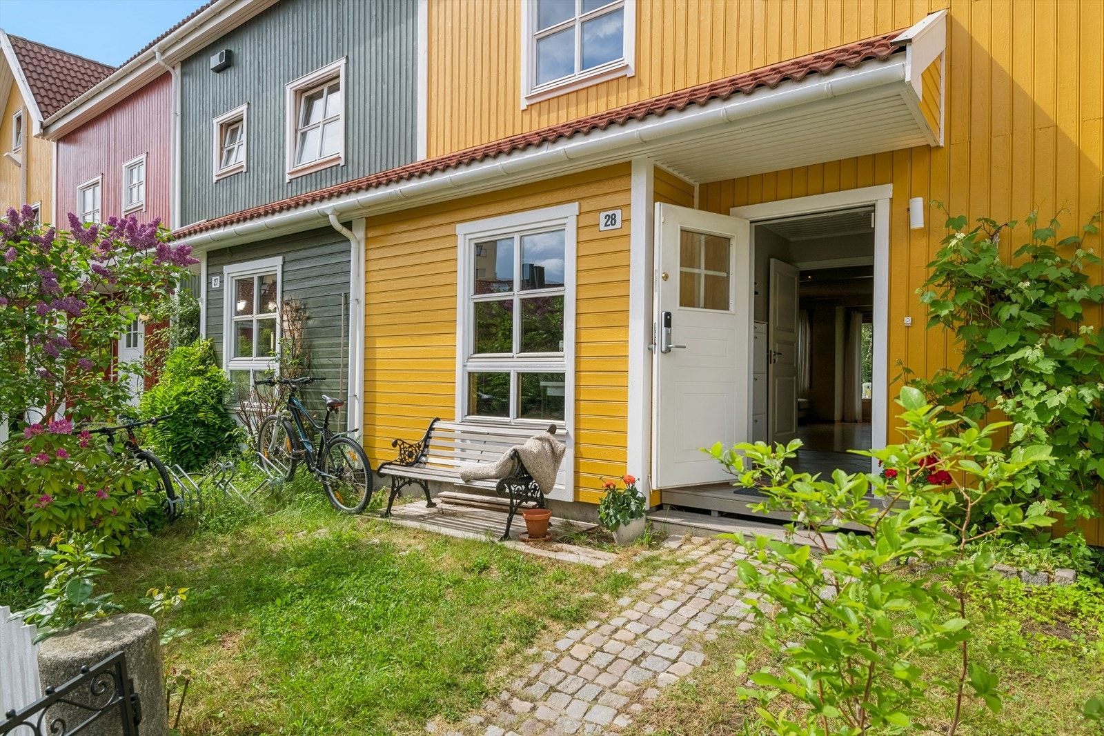 Inngangspartiet er opparbeidet med plen, beplantning og brostein. Galleribilde