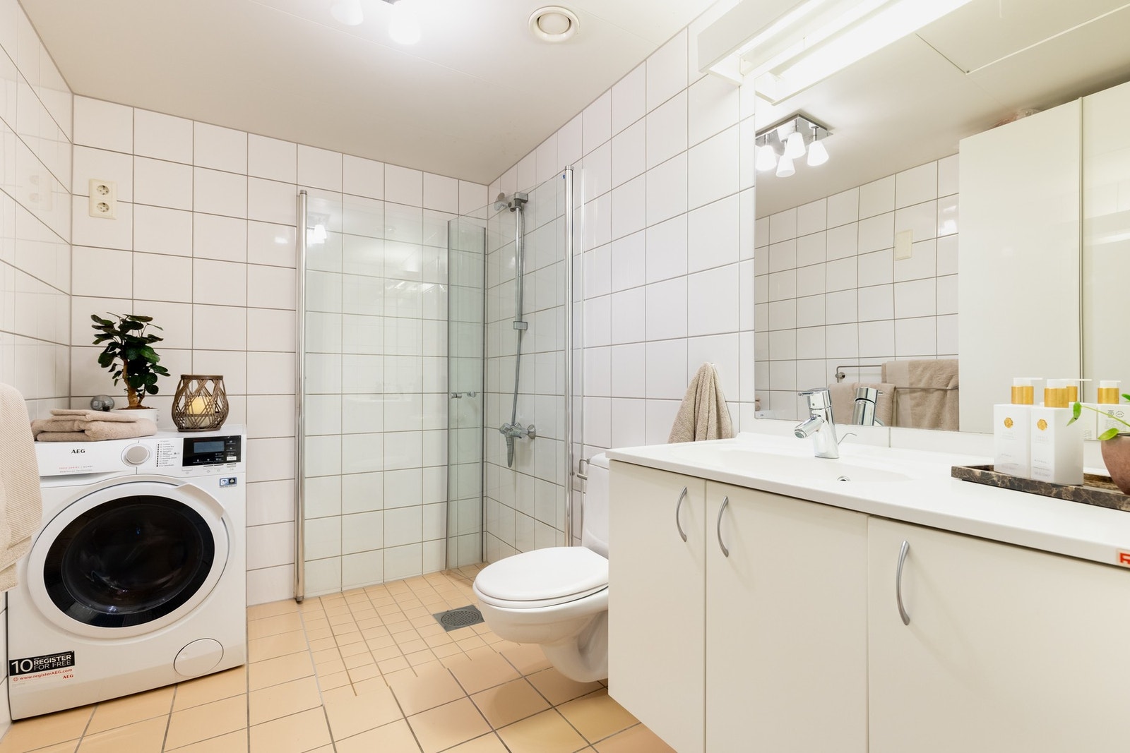 Lyst, flislagt baderom med varme i gulv og opplegg for vaskemaskin. Galleribilde