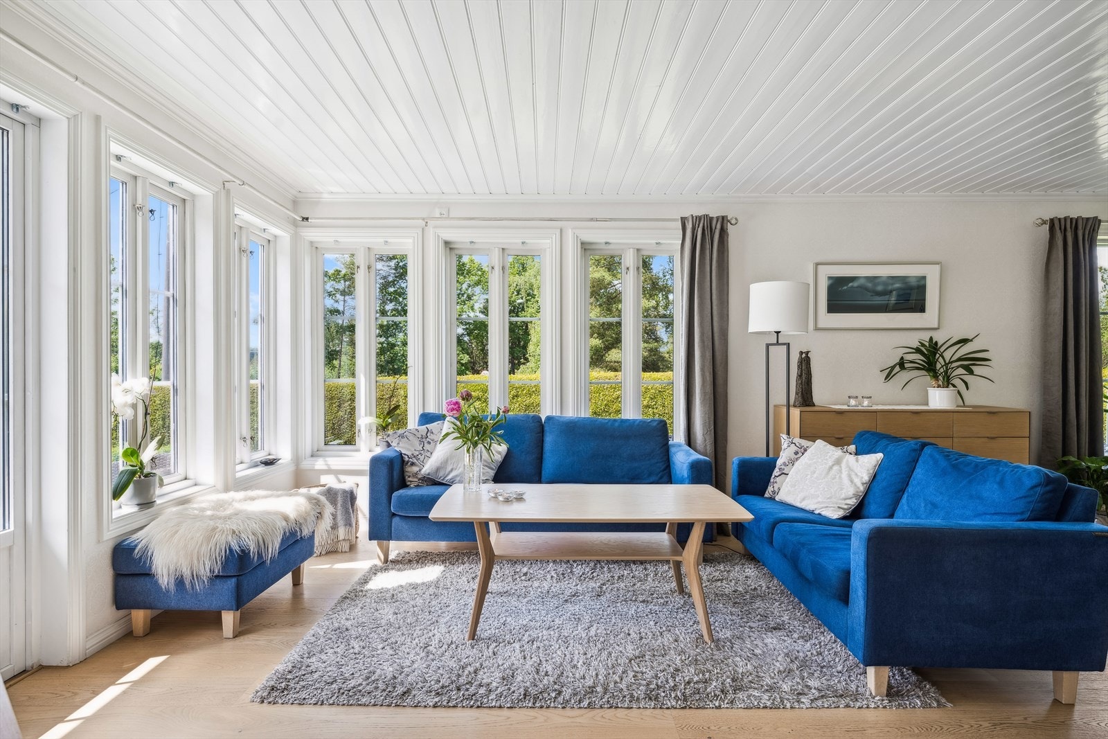 Stuen i første har et bredt vindusbånd av høyreiste vinduer og terrassedør i hjørnet av stuen er både sjarmerende og sørger for fin forbindelse til terrassen og den grønne hagen utenfor. Galleribilde