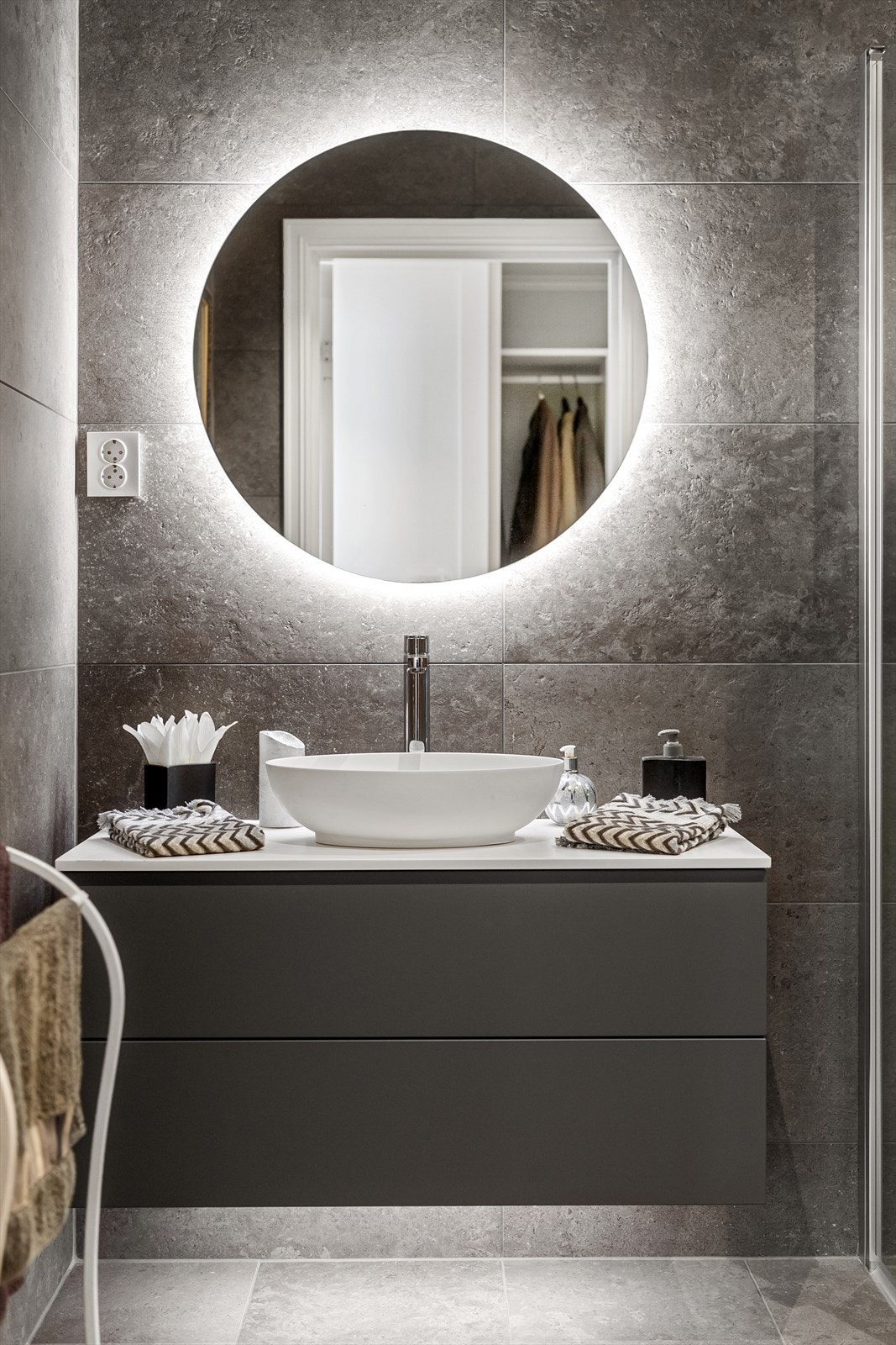 Innredning med folierte fronter, benkeplate i laminat med overliggende servant og speil med belysning. Galleribilde