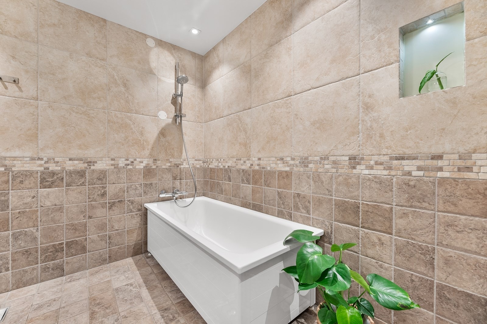 Badet er utstyrt med badekar med dusj, vegghengt wc og servantinnredning med hylle Galleribilde