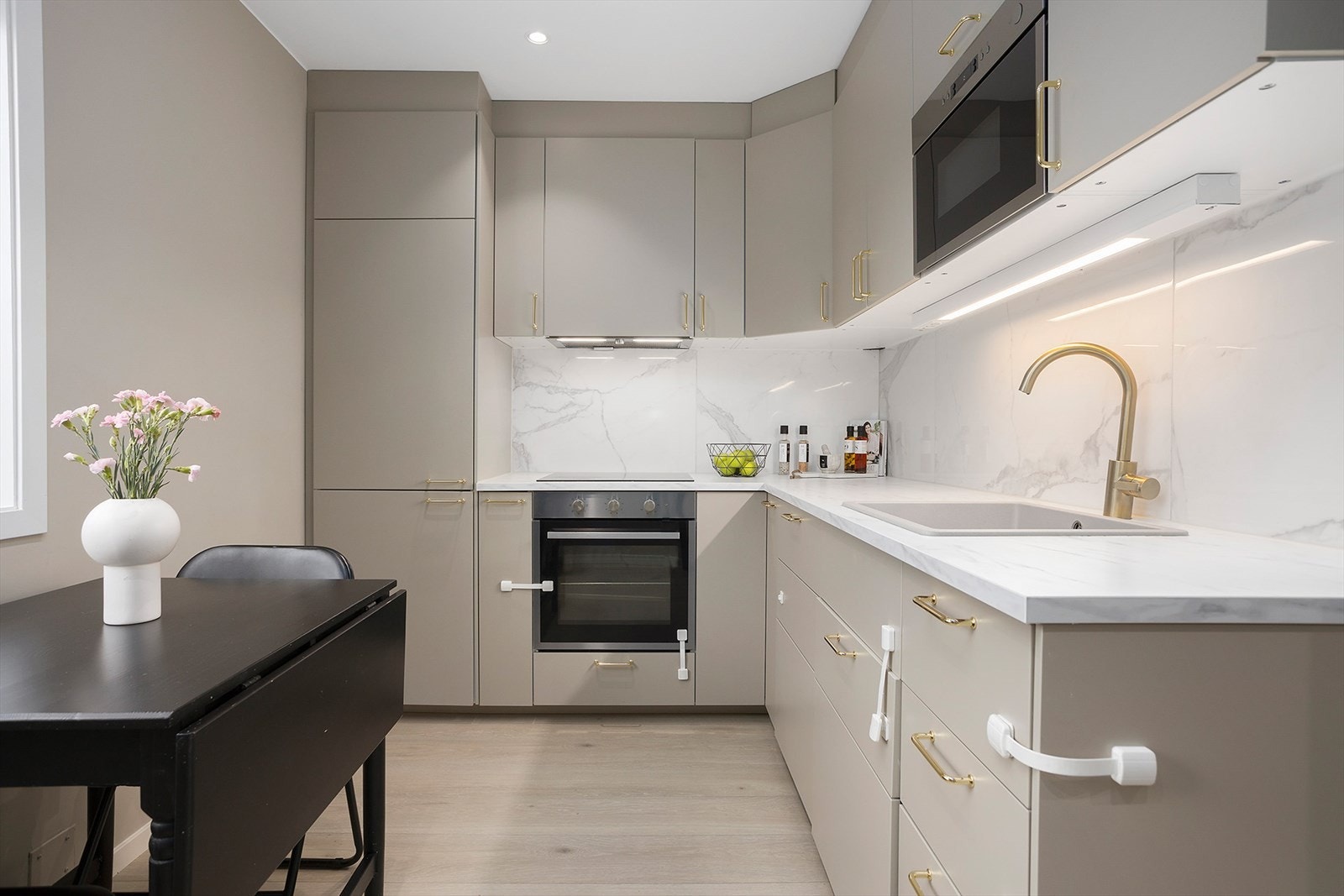 Delikat kjøkken i klassisk L-form med slette fronter, benkeplate i laminat og lekre detaljer. Galleribilde