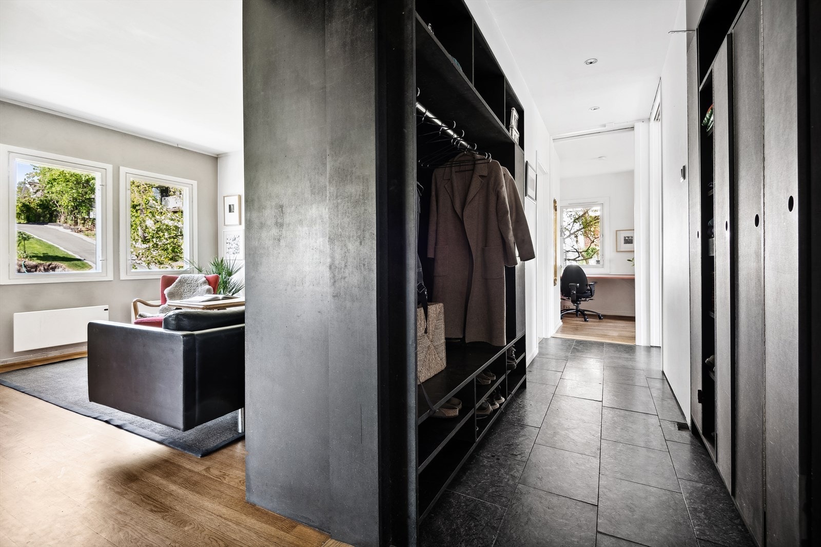 Fra entreen tar man seg videre inn til en praktisk mellomgang med mye oppbevaringsplass i åpen garderobeløsning og skap t.h. Galleribilde