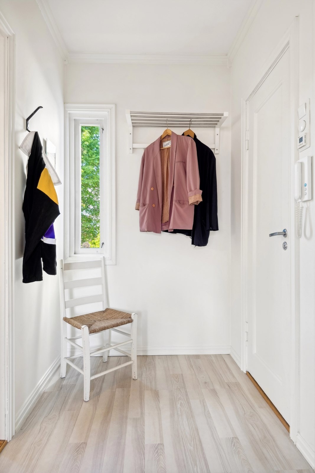 Innbydende entré med portåpner og plass for å henge fra seg yttertøy. Lite vindu med utsyn mot idyllisk bakgård. Galleribilde