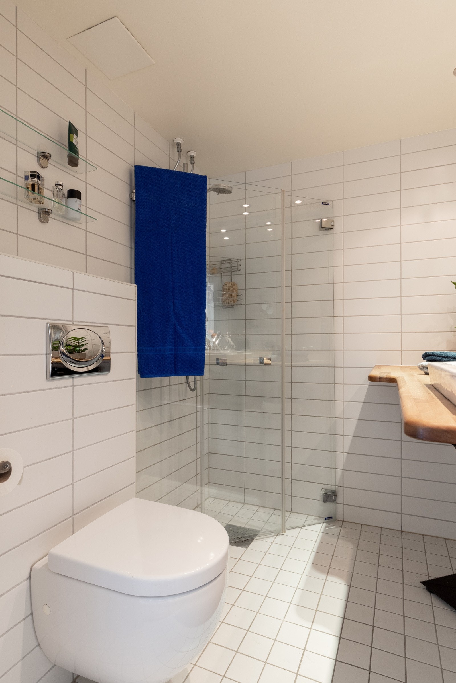 Flislagt gulv med gulvvarme og flislagte vegger, samt nedsenket himling med downlights Galleribilde