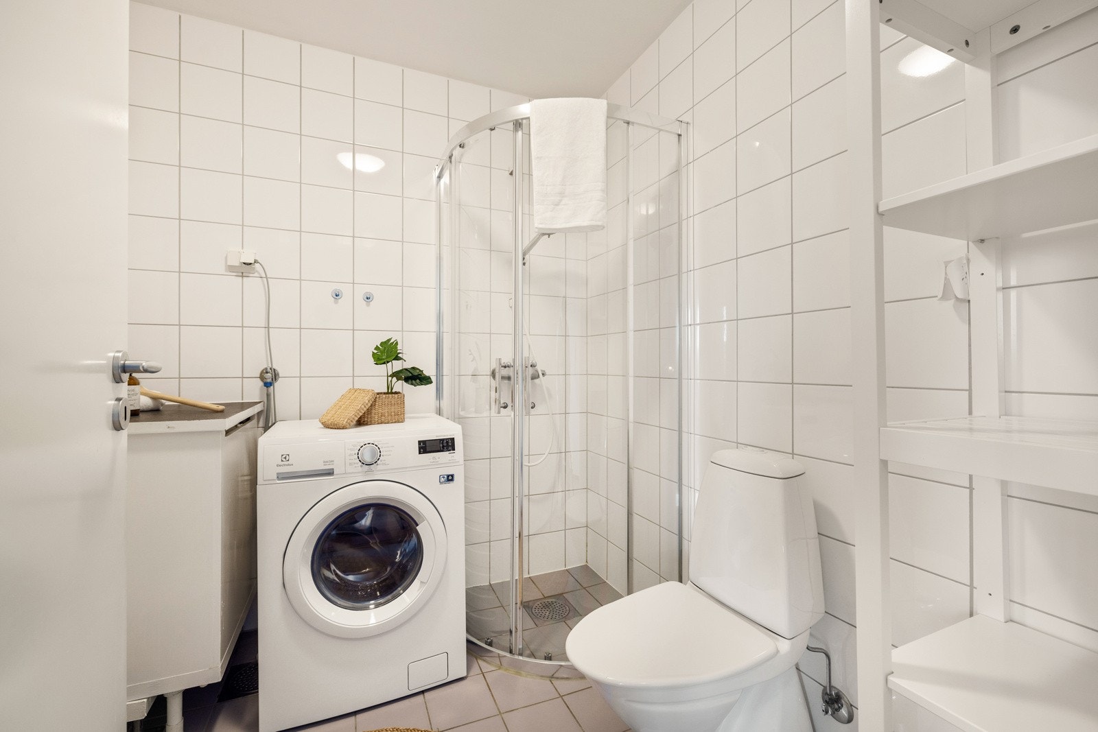Badet er innredet med toalett, dusj i dusjhjørne av glass, innredning med servant, og opplegg til vaskemaskin. Galleribilde