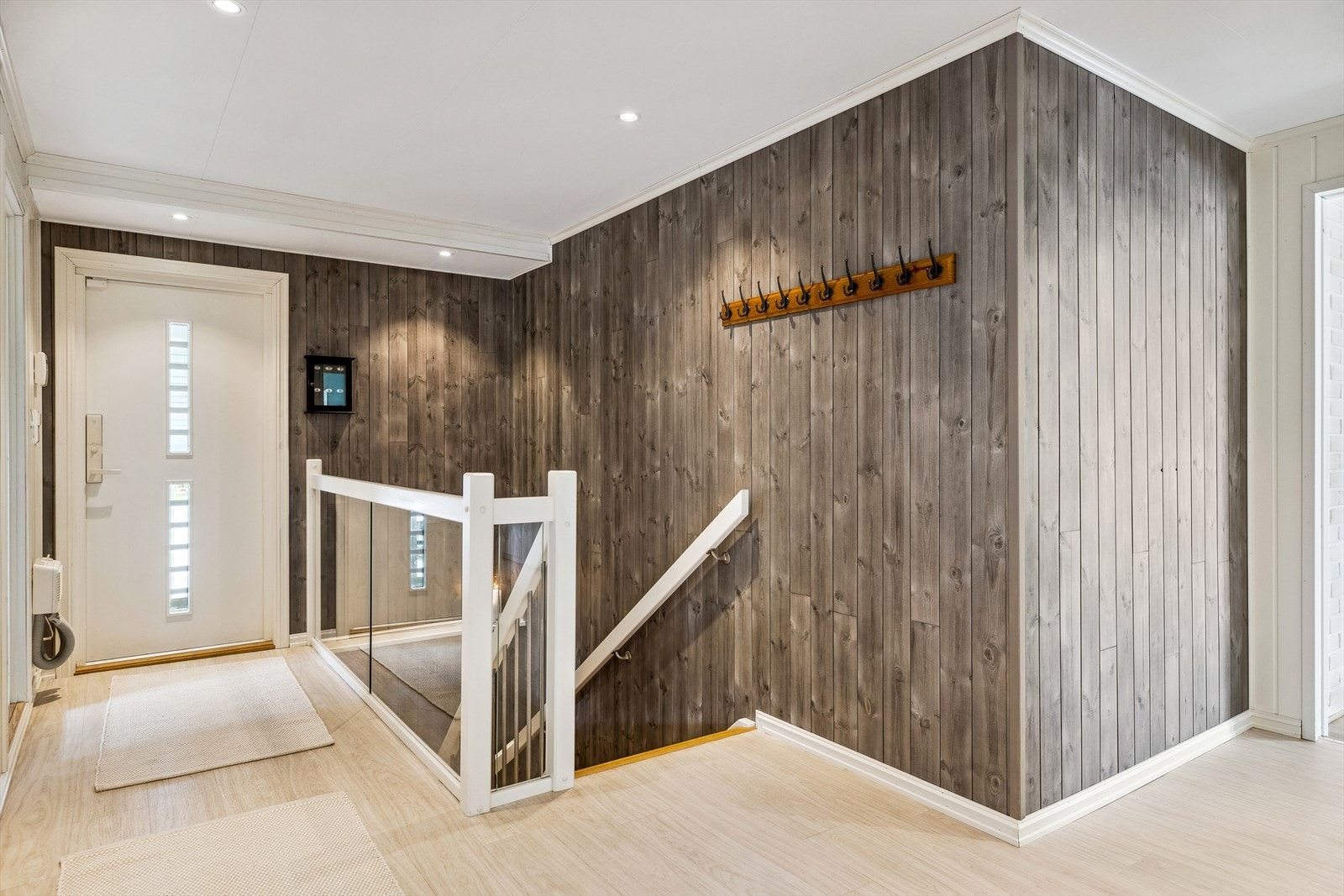 Entreen har en stilfull kombinasjon av hvitmalt- og beiset panel på veggene. Galleribilde