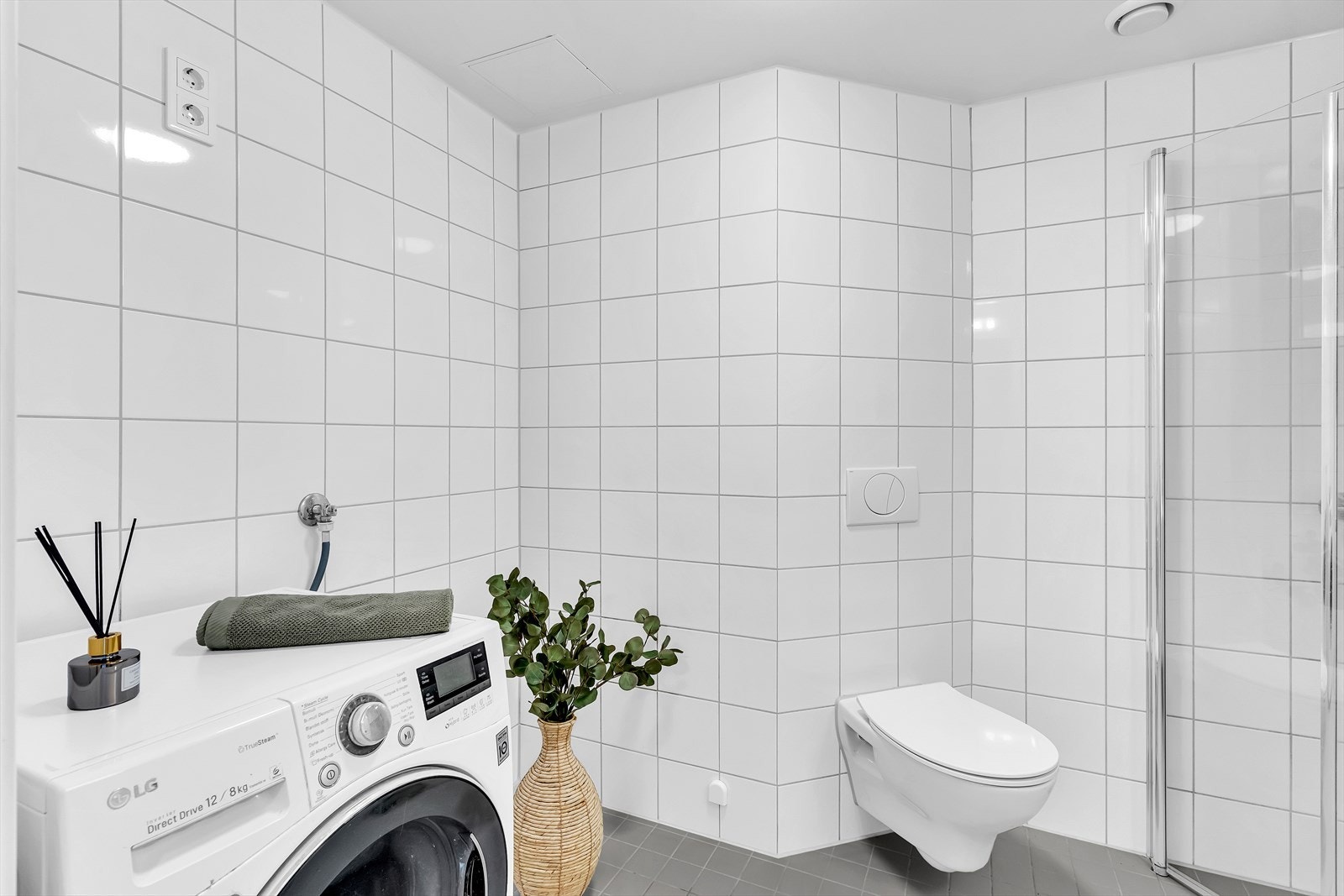 Badet er romslig og har opplegg for vaskemaskin/tørketrommel, dusjnisje med innfellbare glassdører, vegghengt toalett og servantskap. Galleribilde