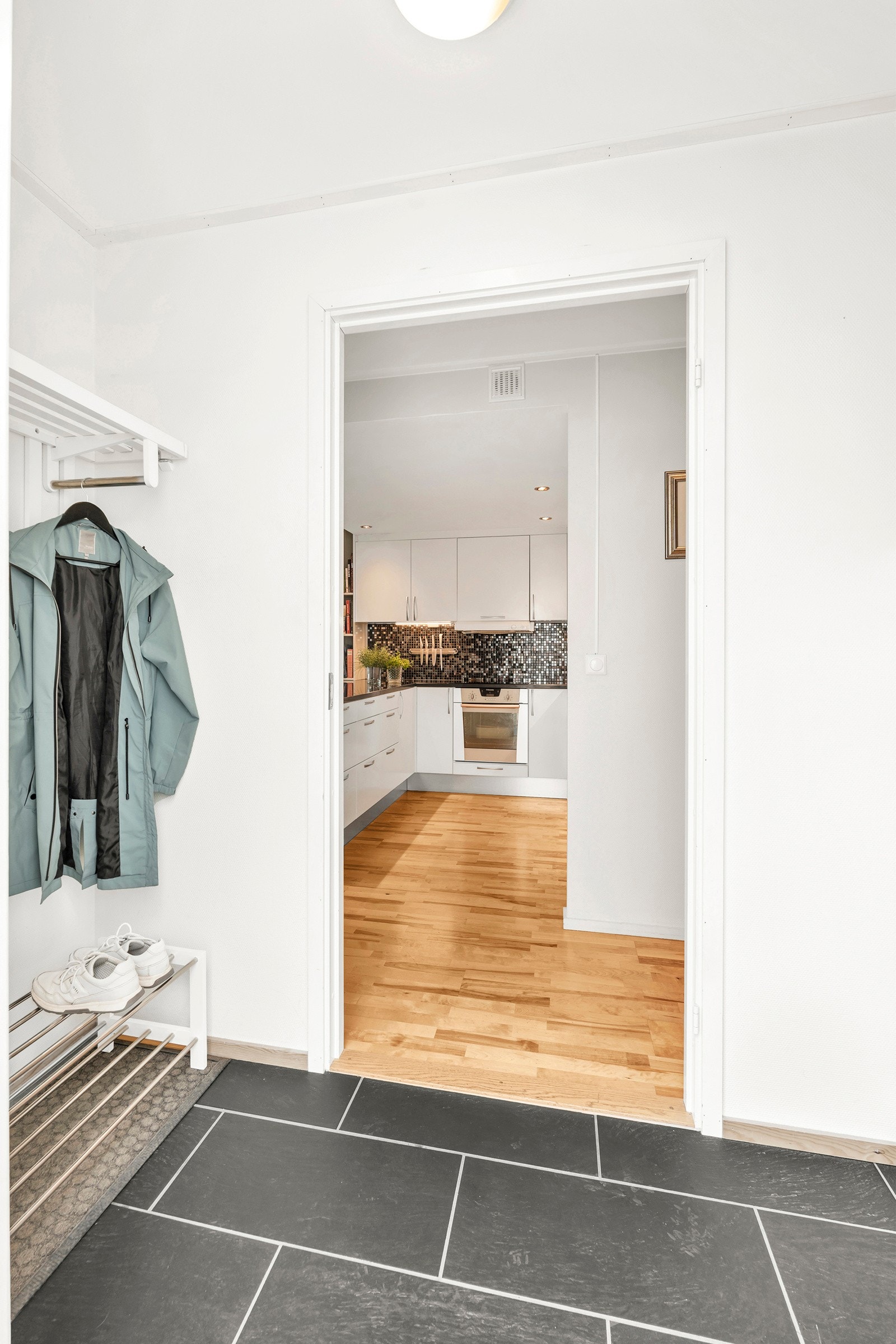 Innbydende entre med fliselagt gulv og klesoppheng. Galleribilde