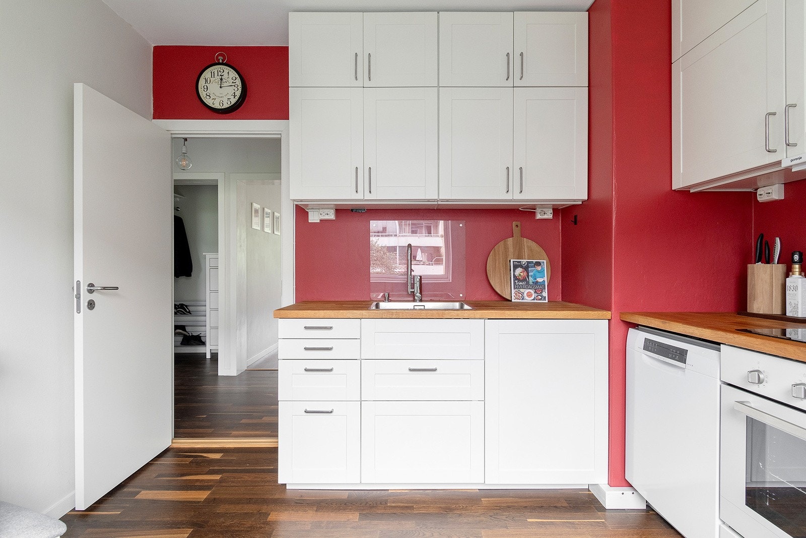 IKEA kjøkkeninnredning fra 2013 med ett-speils laminerte skapfronter, benkeplate i tre, enkel oppvaskkum, ventilator og innfelte hvitevarer som koketopp og stekeovn, og frittstående oppvaskmaskin og kjøl/- fryseskap Galleribilde