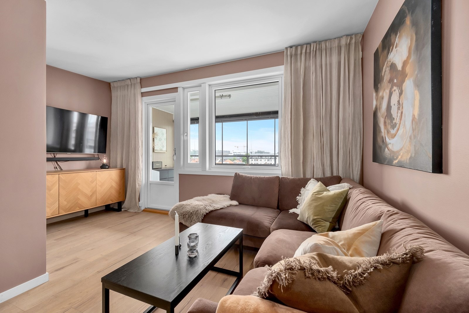 Videre er det en balkongdør og vindu som gir lysinntak og sikrer at stuen alltid føles lys og velkommen. Galleribilde