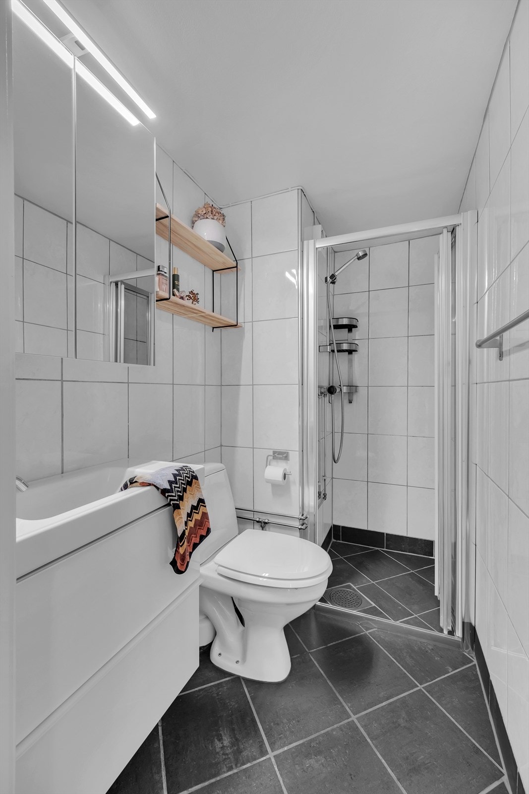 Badet i leiligheten har fliser som dekker både gulv og vegger. I gulvet er det varmekabler. Galleribilde