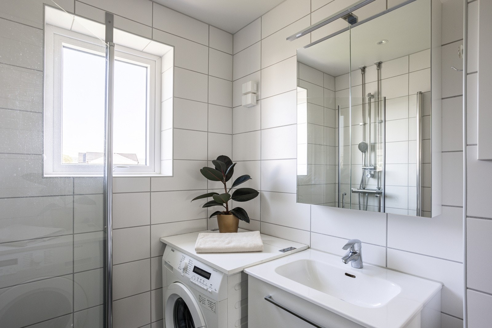 Moderne baderomsinnredning med skuffer og heldekkende servant, speilskap med belysning over. Plass og opplegg for vaskemaskin og tørketrommel over om ønskelig. Galleribilde