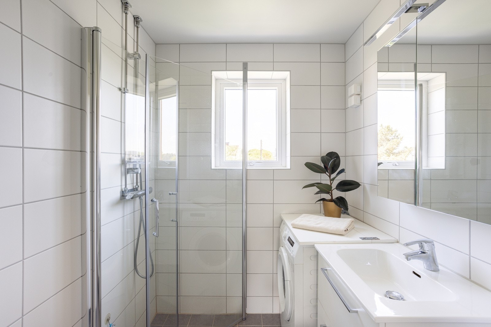 Baderommet har grå fliser på gulv med gulvvarme, hvite fliser på veggene og downlights i himlingen. Galleribilde