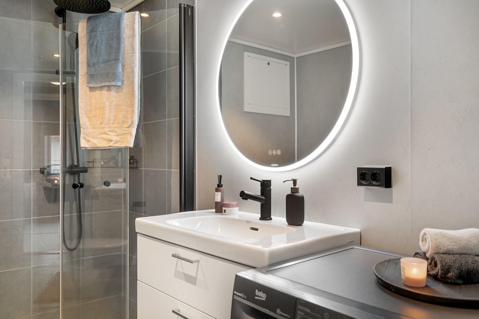 Innredet med vegghengt servantinnredning, ovenpåliggende servant med armatur, vegghengt toalett og dusjhjørne med regndusj. Galleribilde